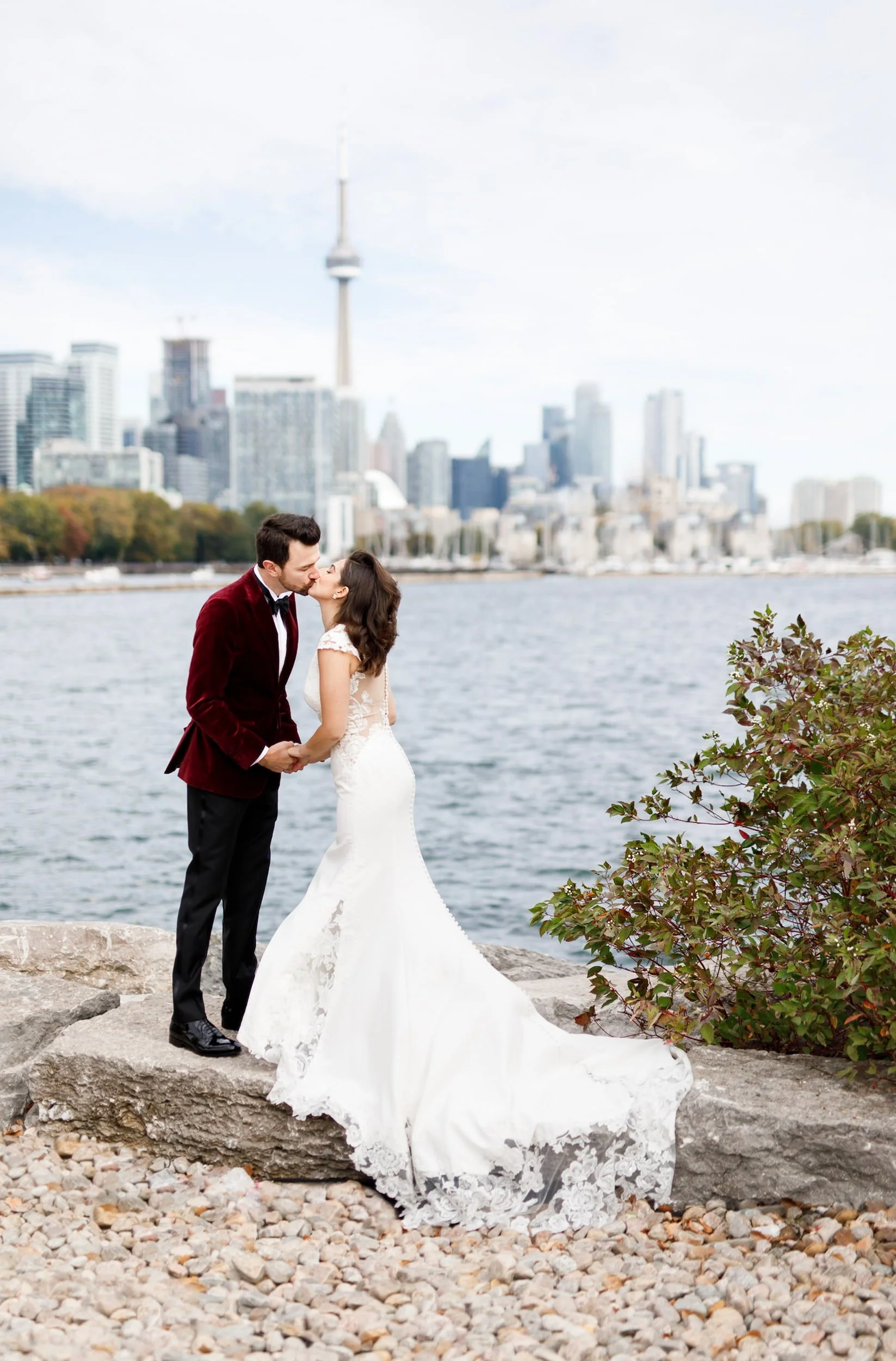 Bride and groom embracing by the water with the Toronto skyline in the background at Trillium Park (Copy)