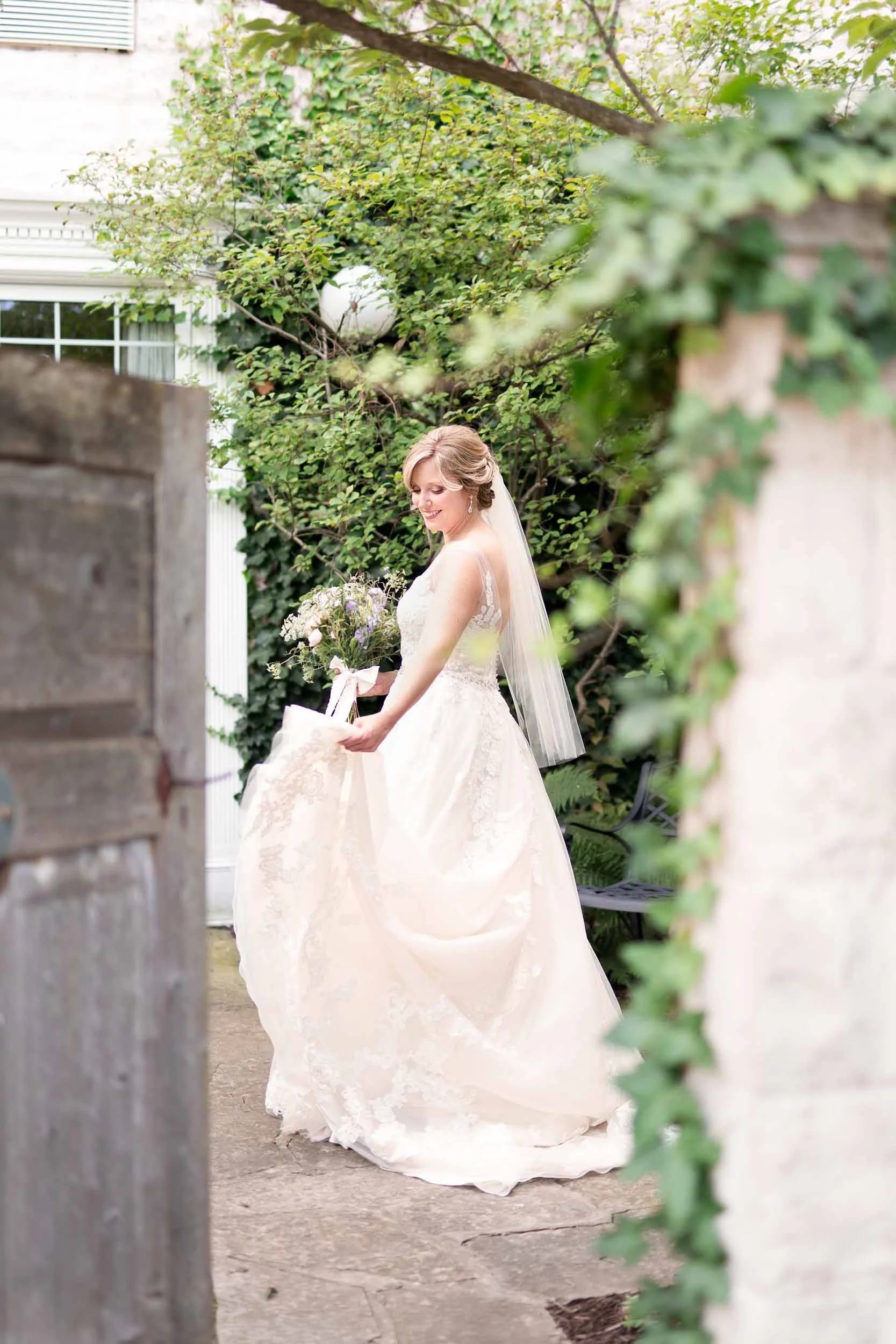 Bride flowing her wedding dress between stone gates at the Inn on the Twenty in Jordan, Ontario (Copy)