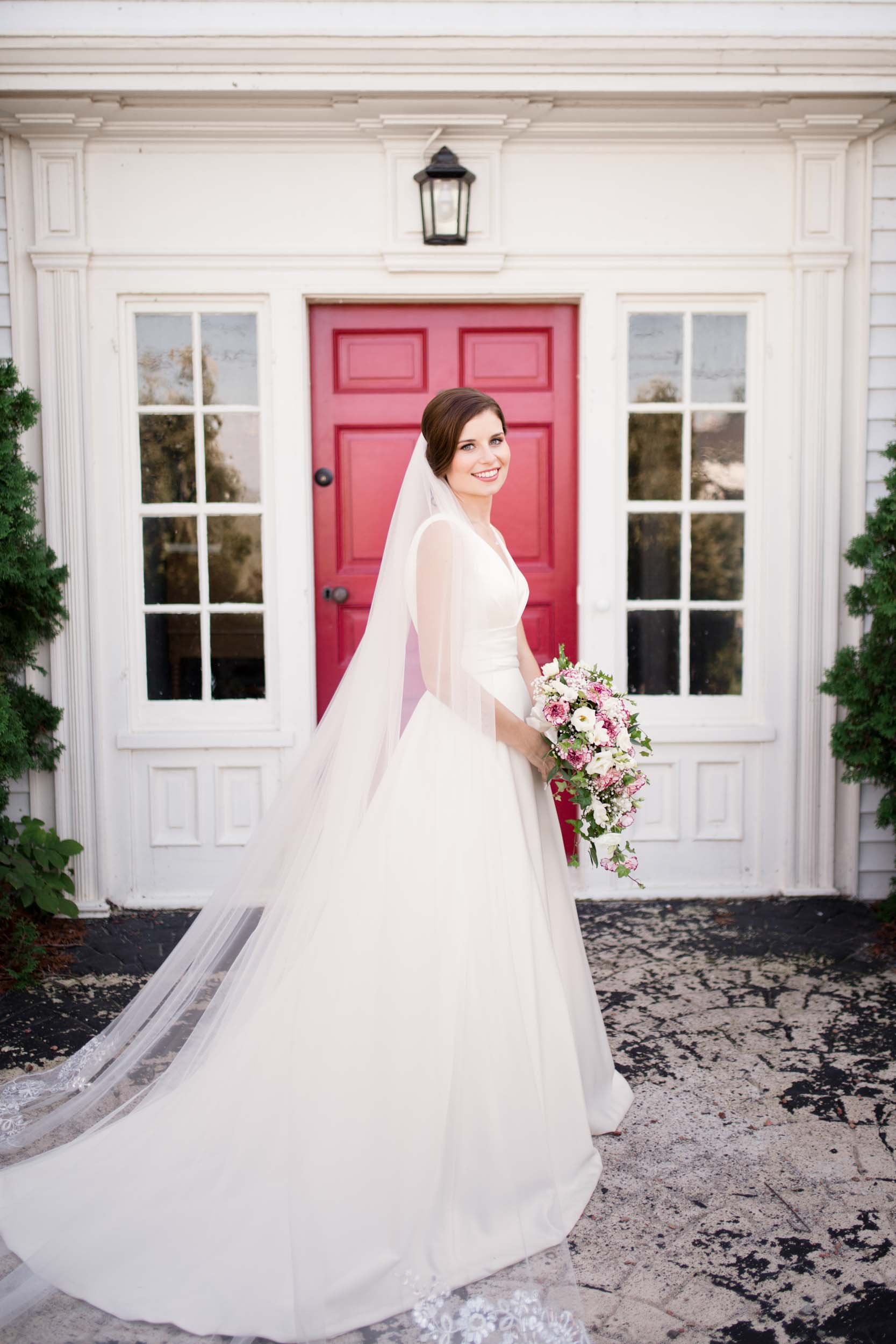 Bride standing in front of the iconic red door at the Jordan House wedding in St. Catharines (Copy)