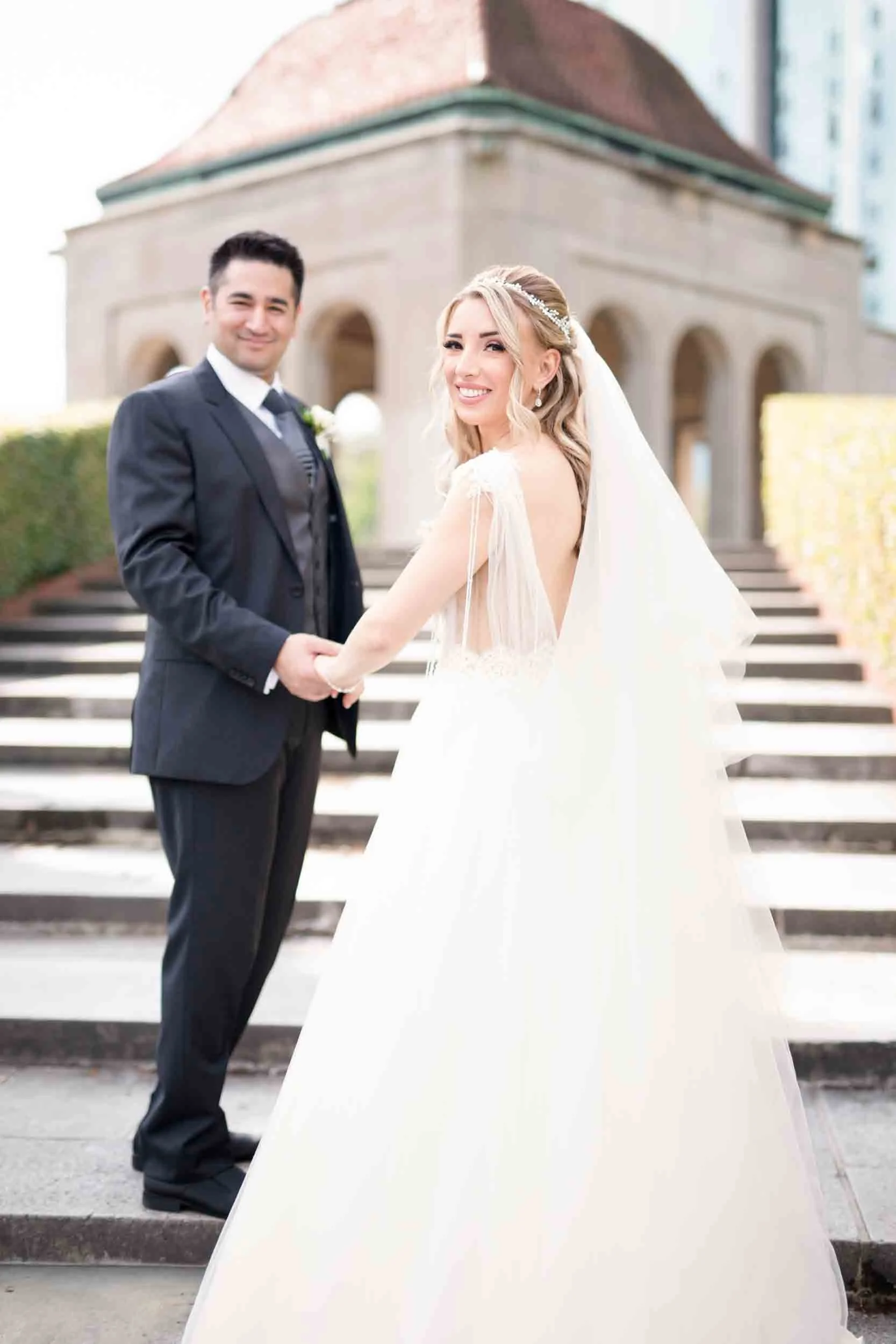 Bride and groom holding hands guiding up the stairs on the steps at Oakes Garden Theatre in Niagara Falls (Copy)