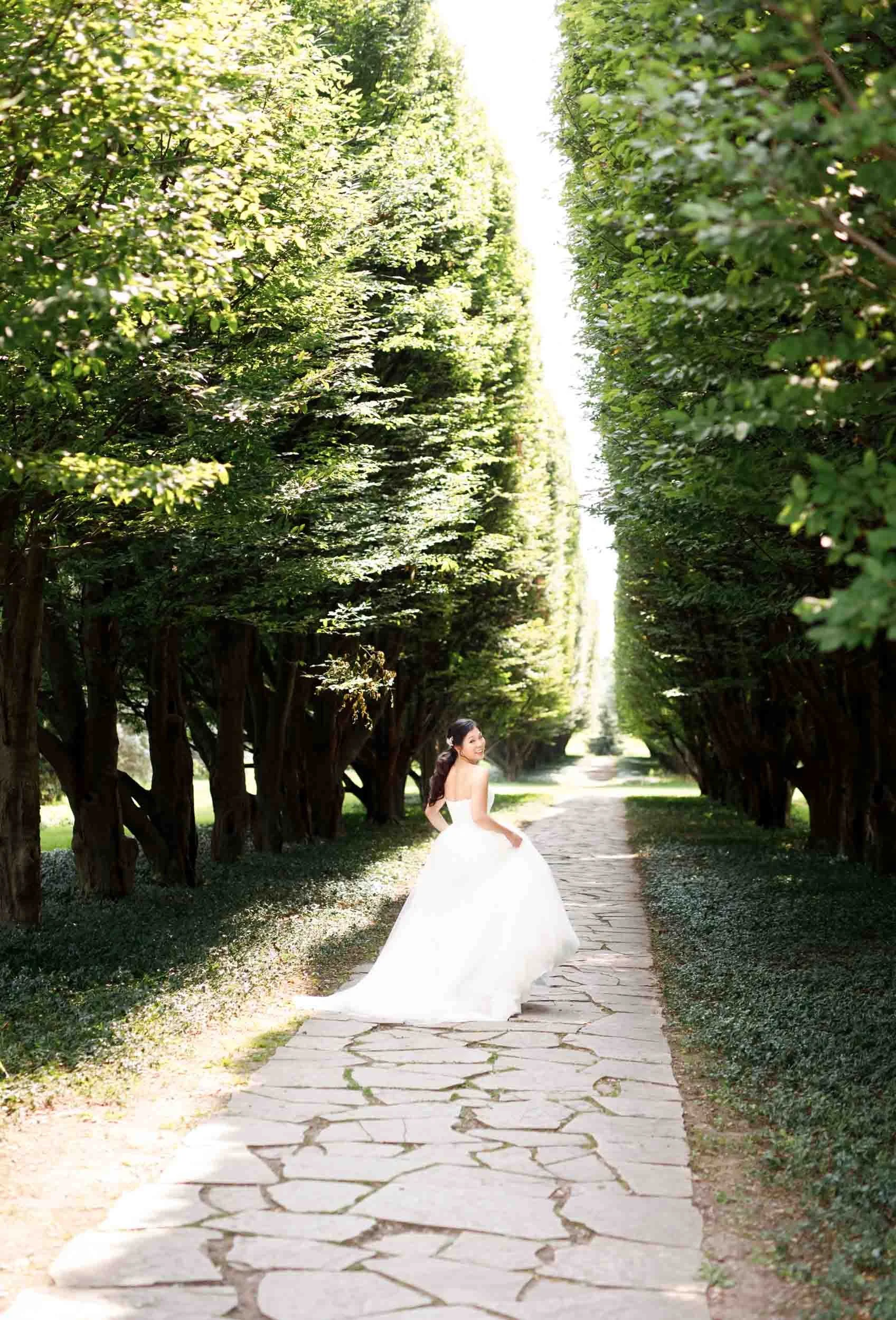 Bride playfully alone down a tree-lined path at Royal Botanical Gardens in Niagara Falls, Ontario (Copy)