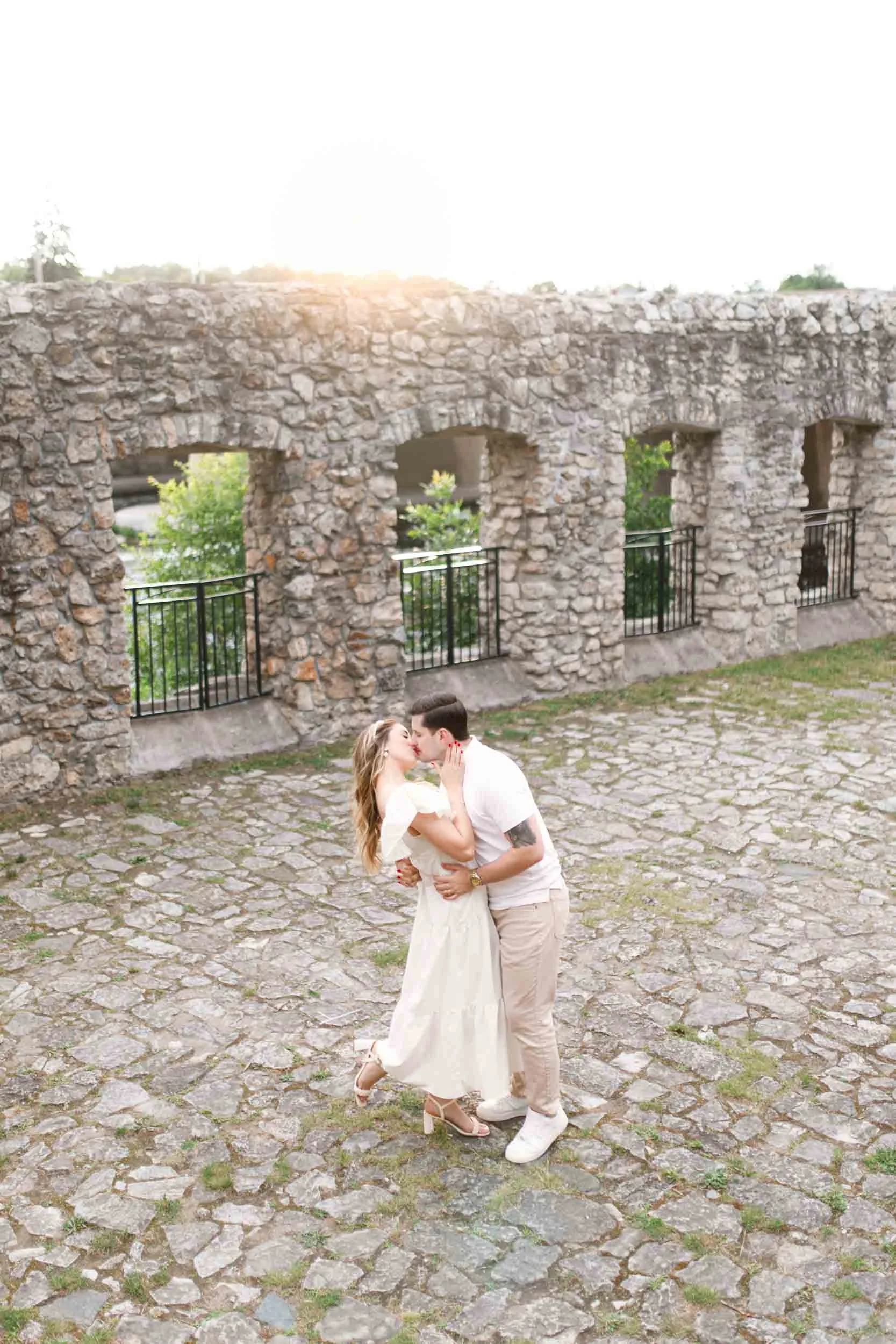 Couple dip and kiss for engagement moment near the stone ruins at Mill Race Park in Cambridge (Copy)