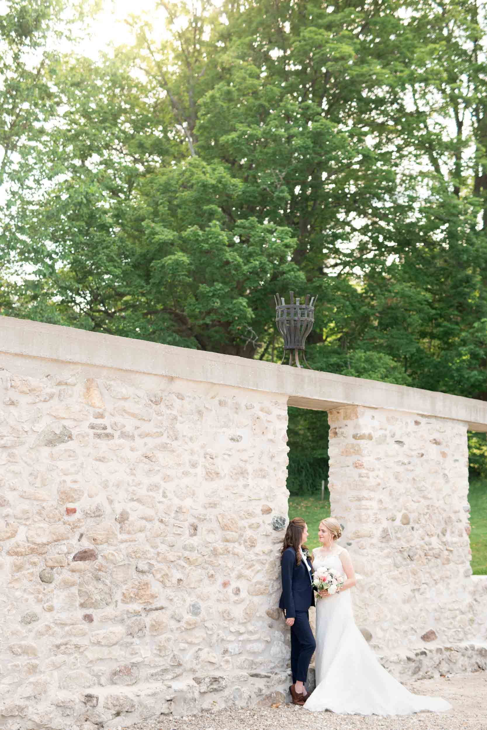 Same-sex couple sharing a quiet moment during a Cambridge wedding against a historic stone wall in Cambridge, Ontario (Copy)