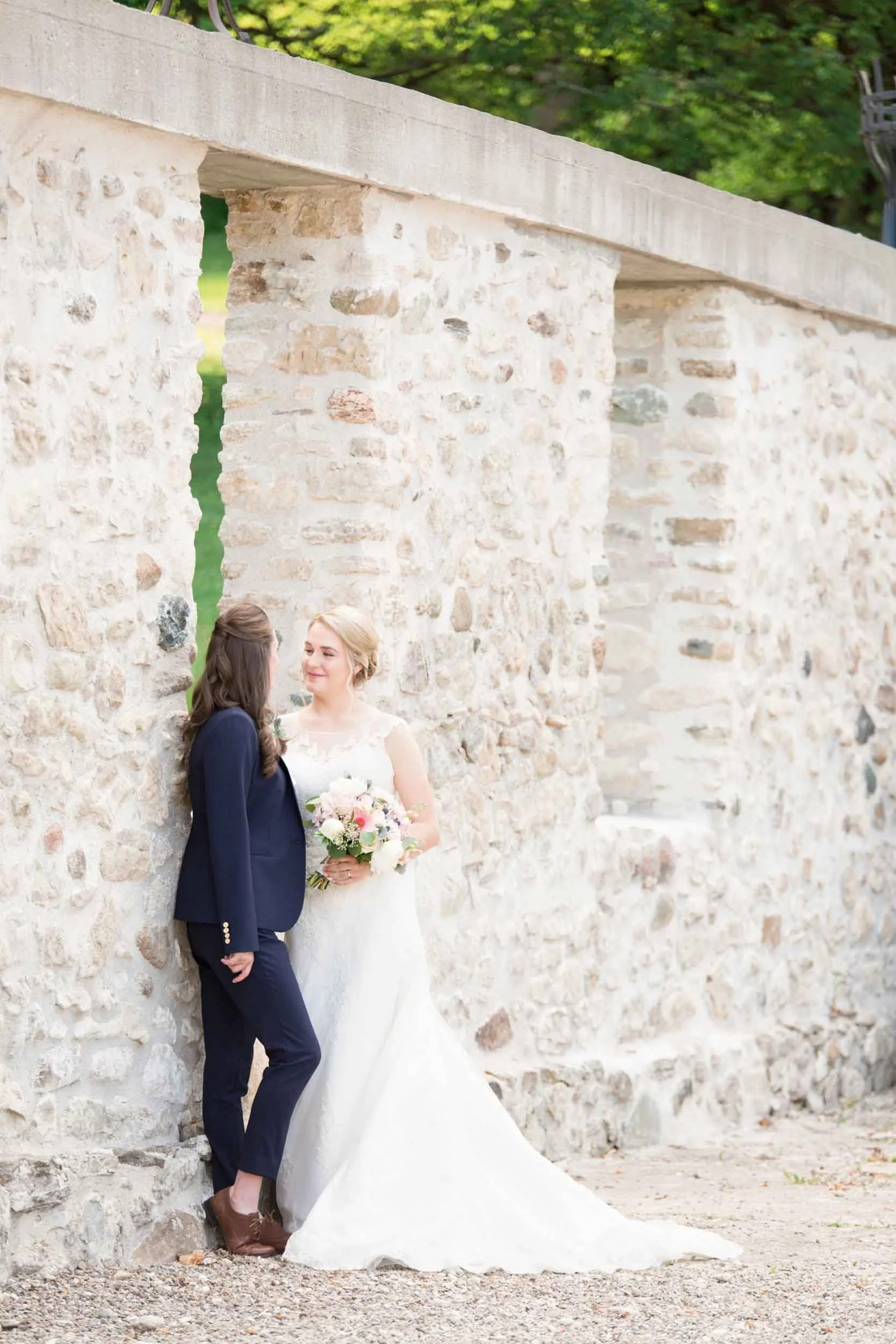 Bride and bride posing together during a classic Cambridge wedding beside a stone wall in the Waterloo Region, Ontario (Copy)