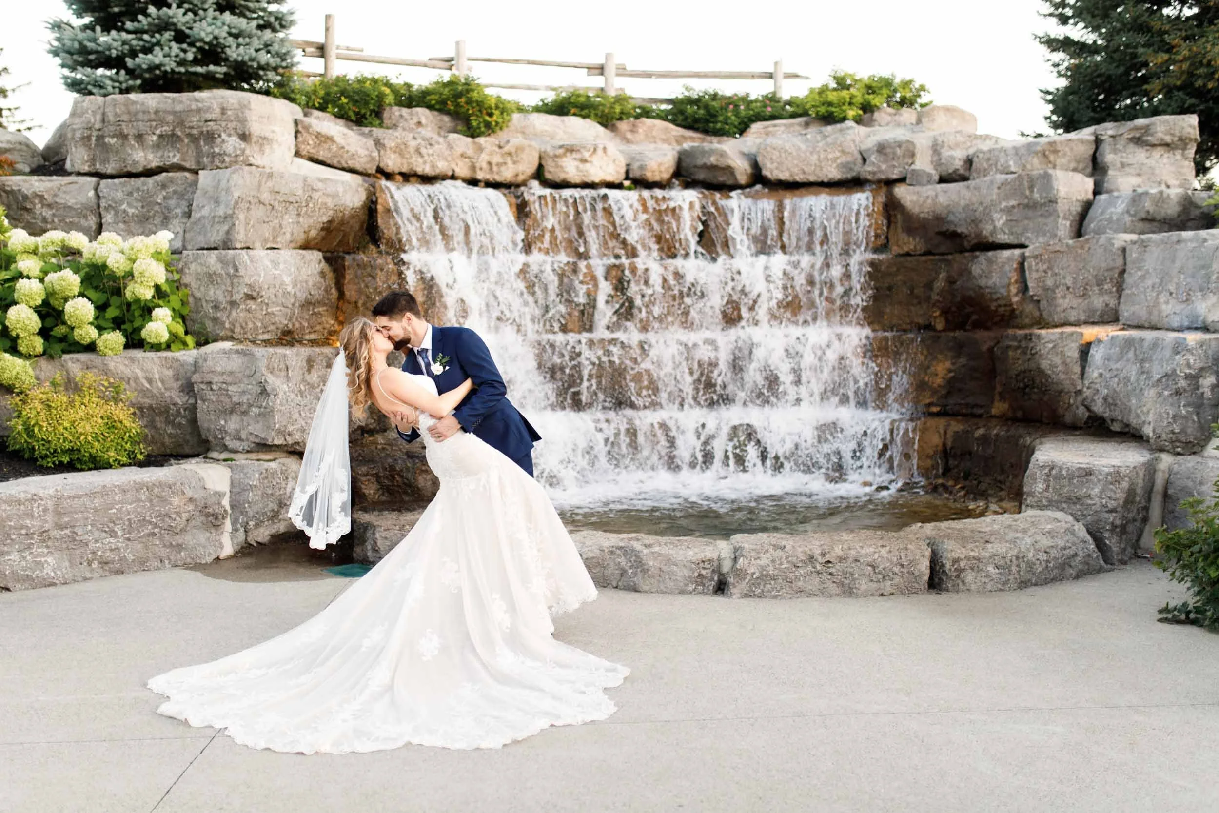 Bride and groom embracing beside the stone waterfall during wedding portraits at Whistle Bear Golf Club in Cambridge (Copy)