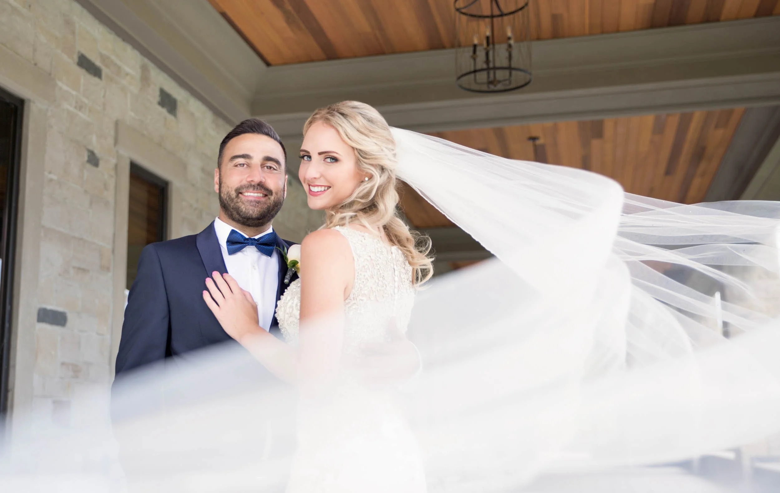 Bride and groom flowing veil portrait beneath the Arlington Estate covered terrace in Vaughan