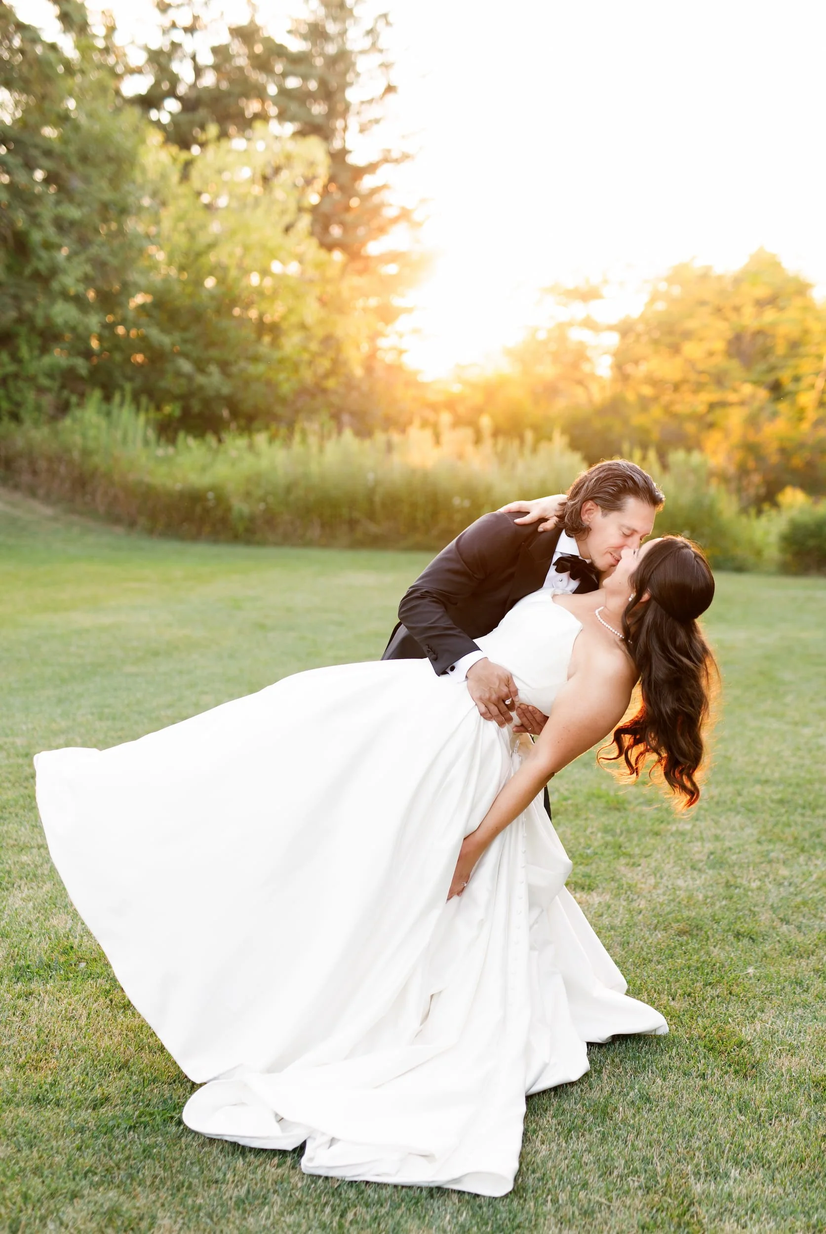 Groom dipping bride in warm evening light on the lawn at The Manor Event Venue in King, Ontario