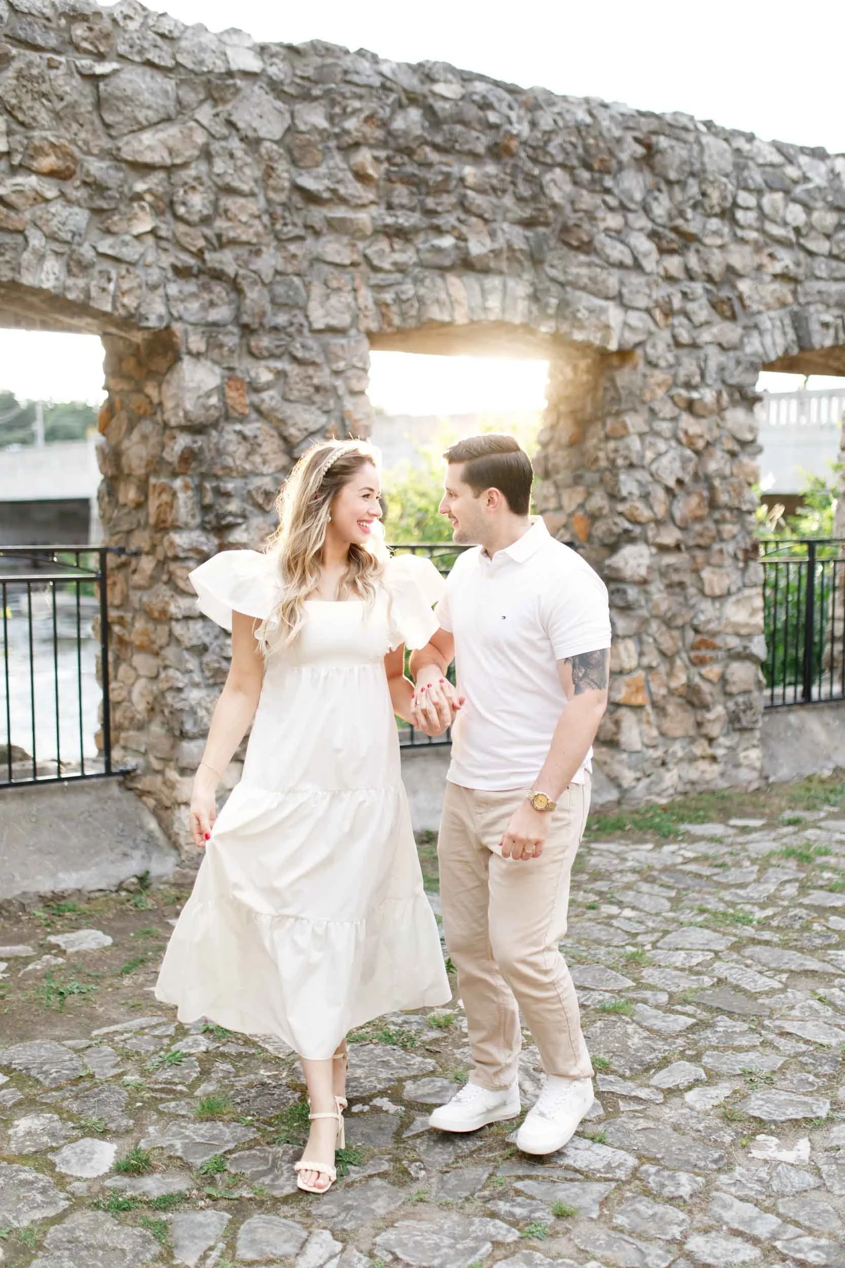 Couple walking beneath historic stone arches near Cambridge Mill in Cambridge, Ontario