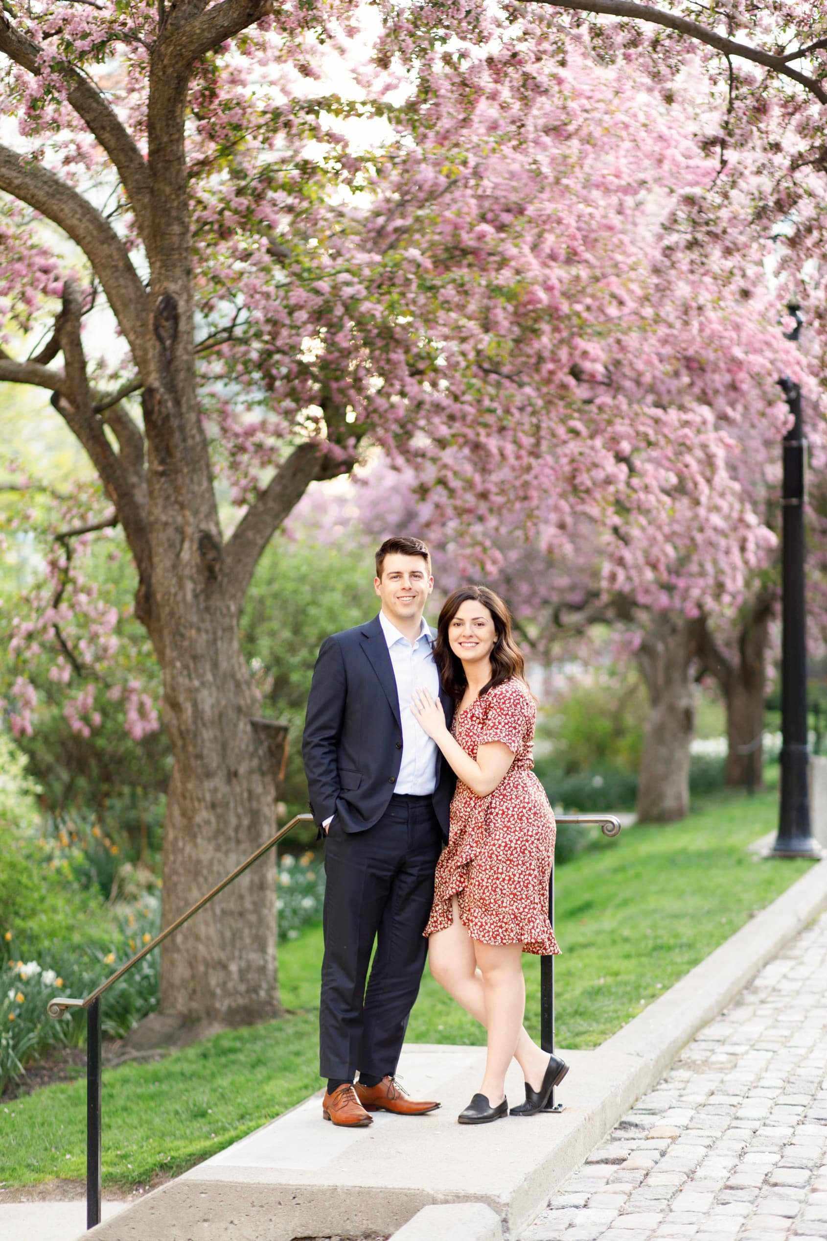 Spring engagement portrait beneath flowering trees at Osgoode Hall courtyard