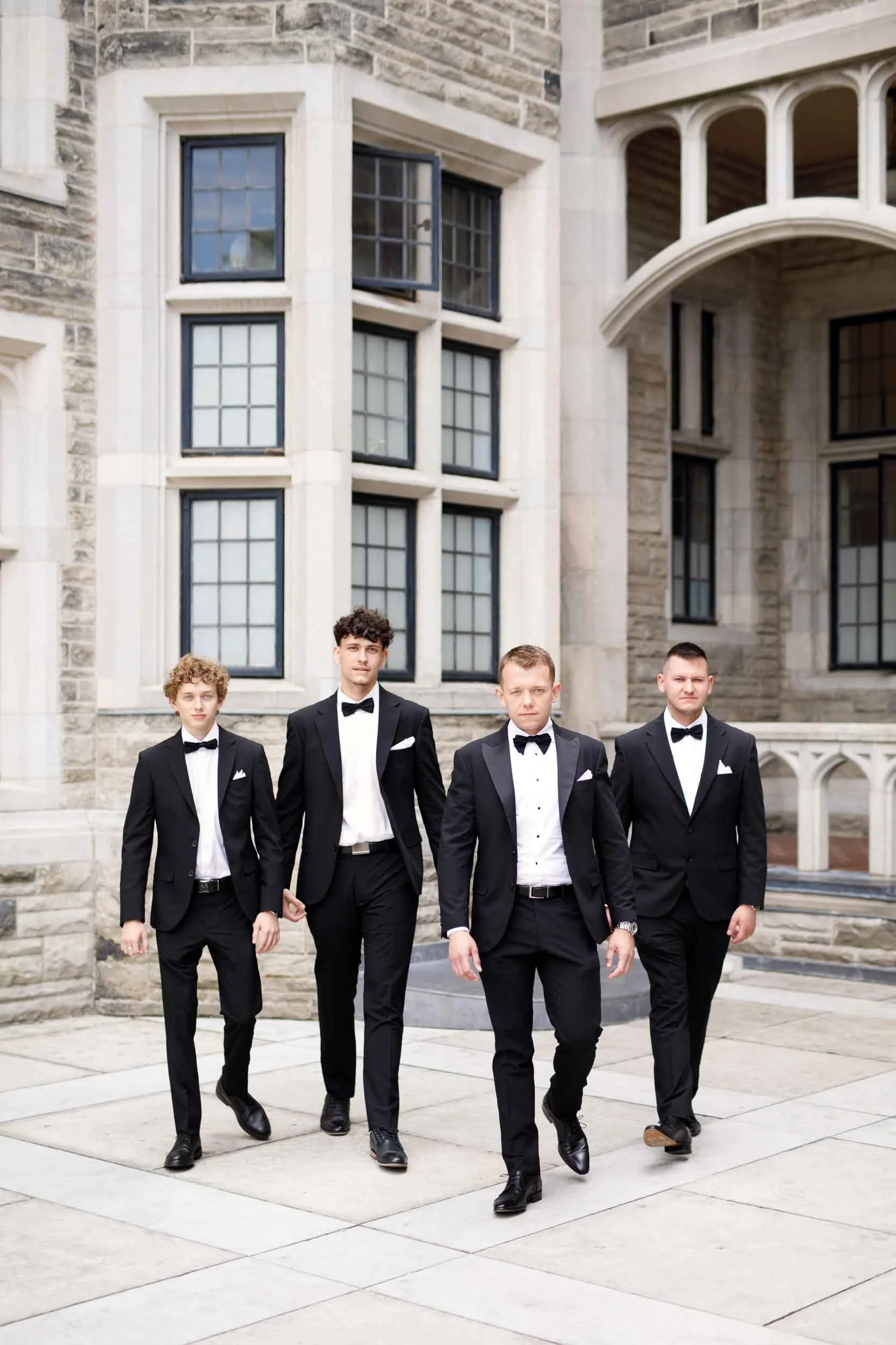 Groomsmen walking across Casa Loma courtyard