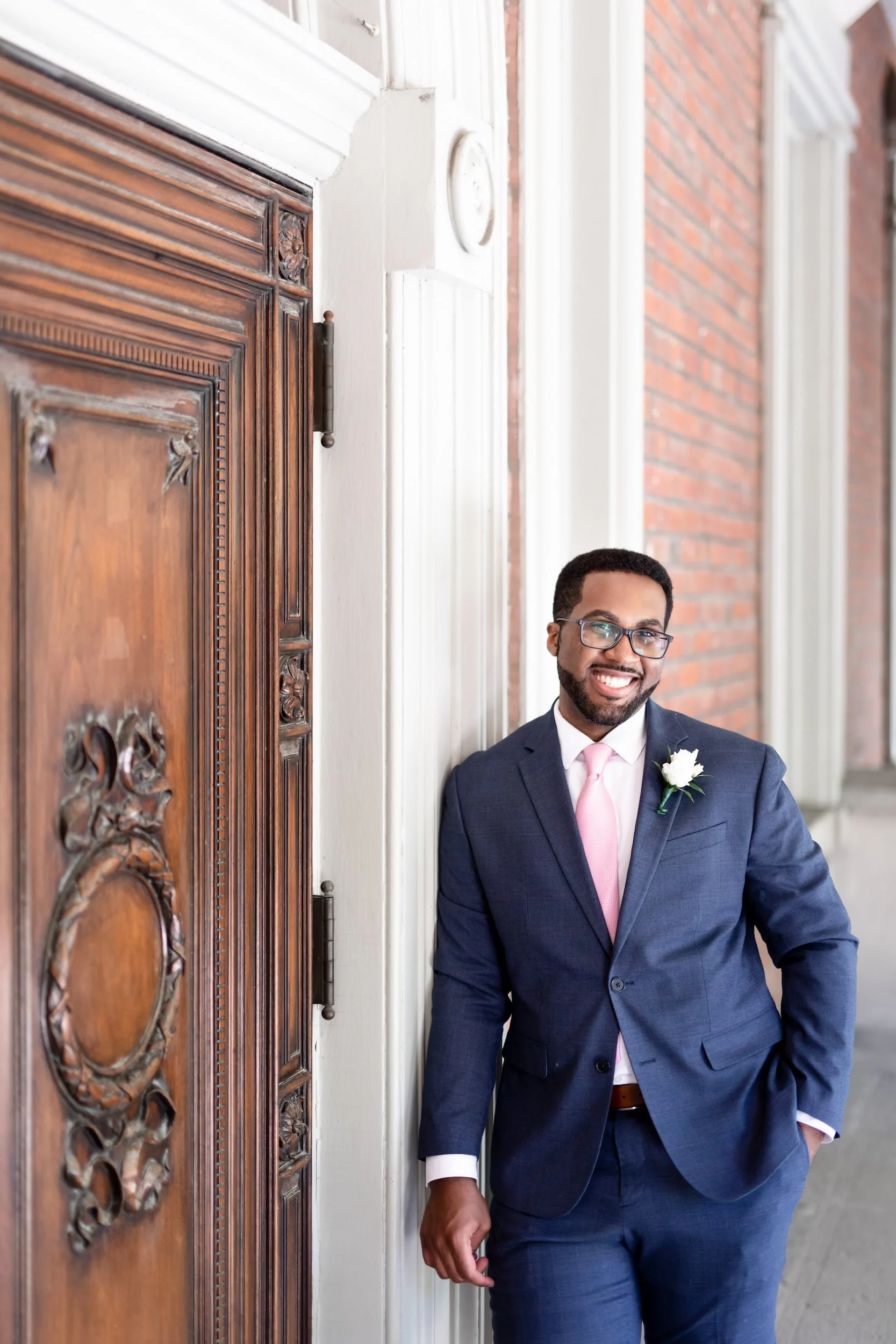 Groom portrait at ornate wooden courthouse doors at Osgoode Hall in downtown Toronto