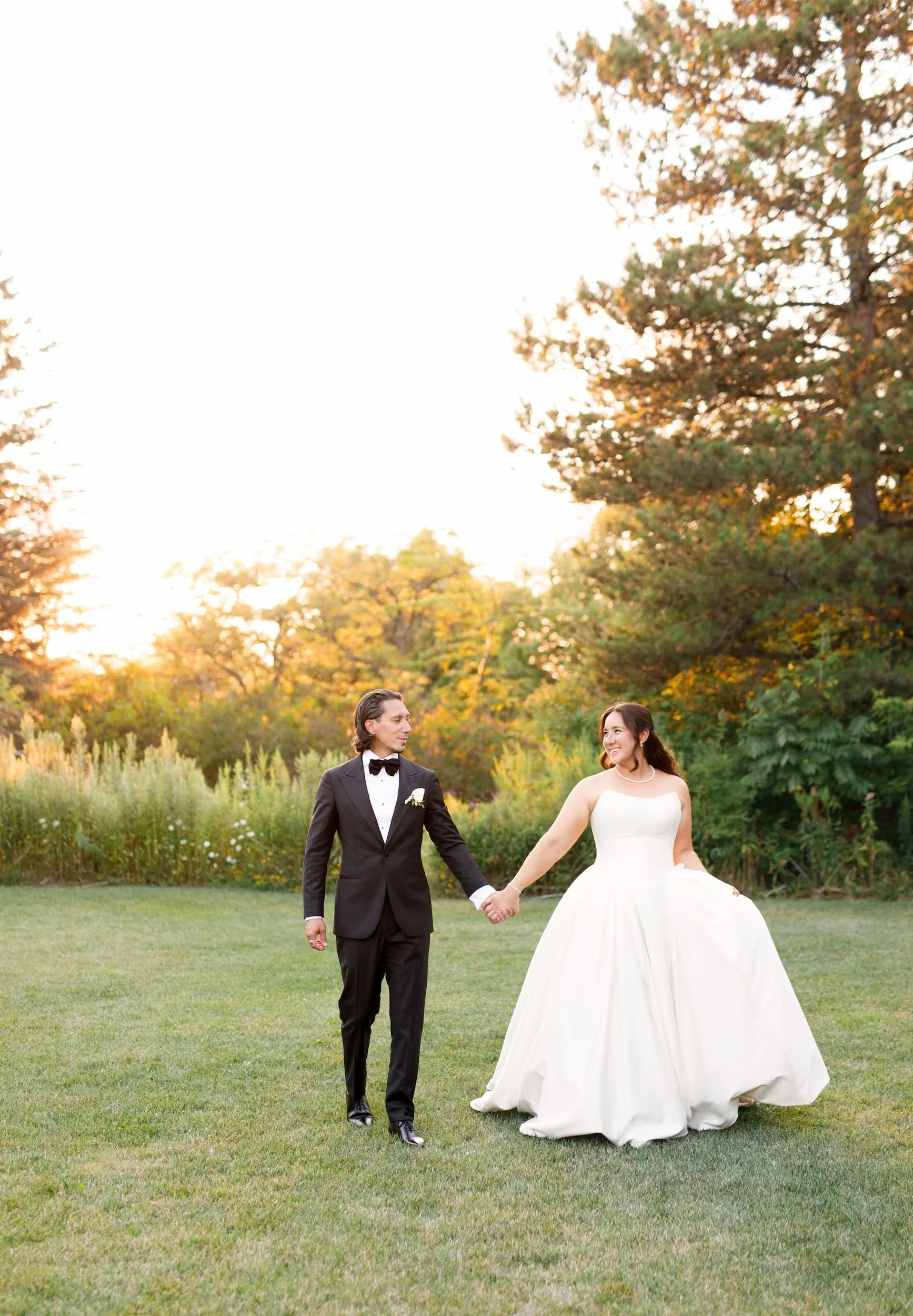 Bride and groom holding hands during sunset portraits at The Manor Event Venue wedding in King, Ontario