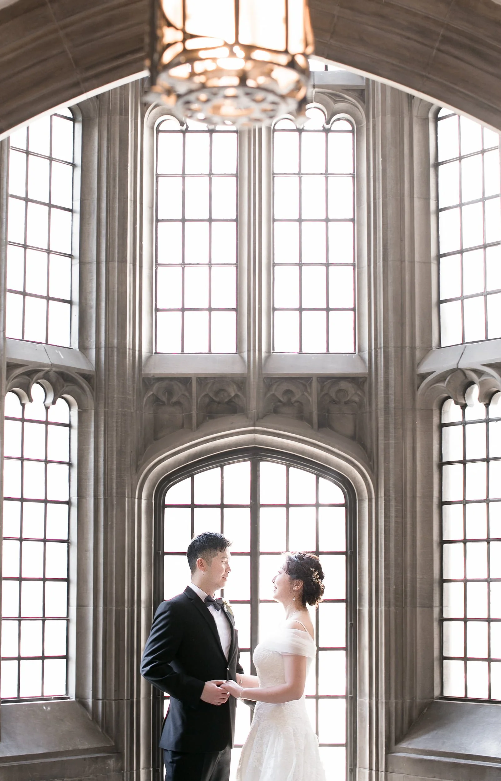 Bride and groom by tall arched windows at Knox College, University of Toronto in Toronto, Ontario
