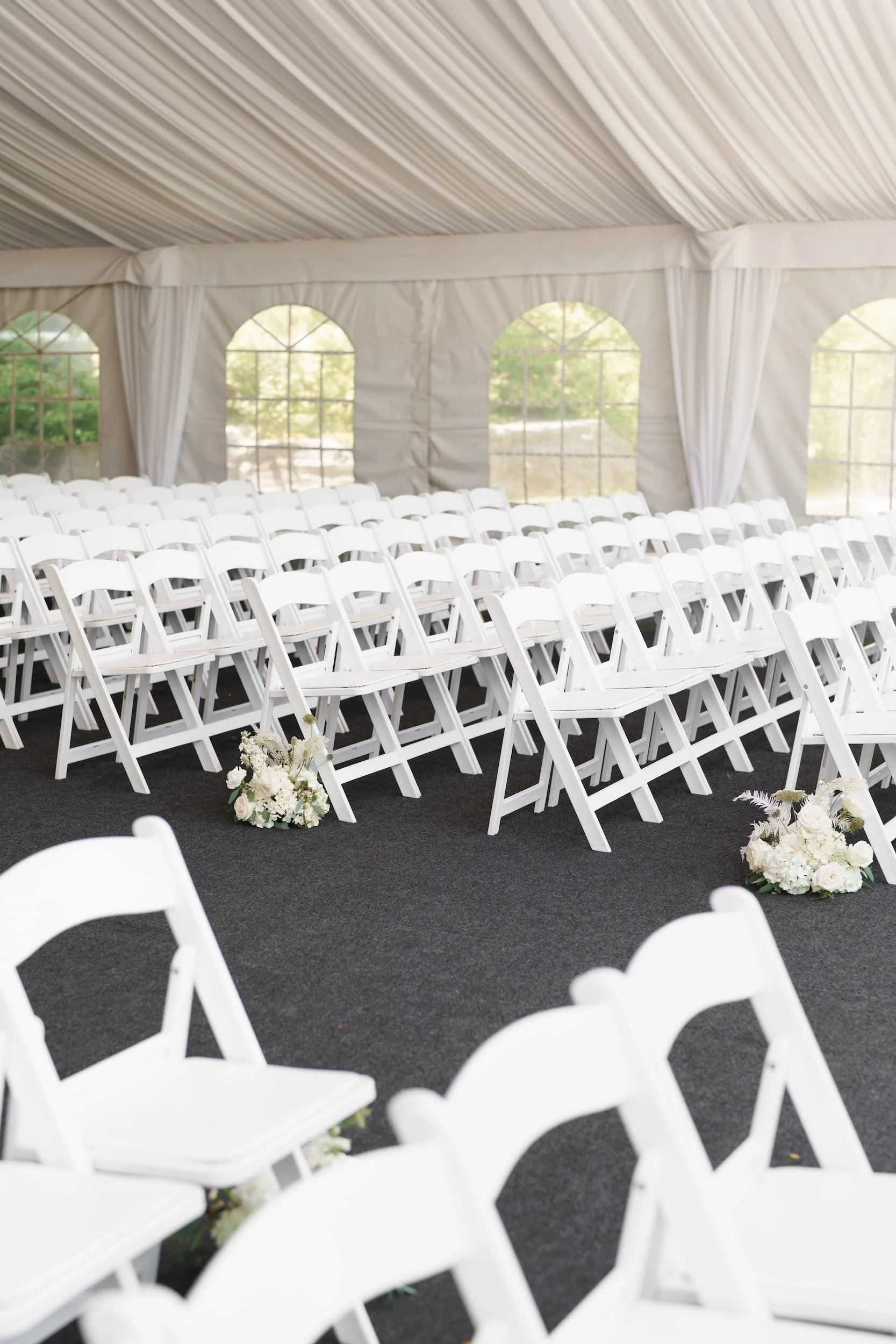 White folding chairs arranged beneath reception tent for The Manor Event Venue wedding ceremony in King, Ontario