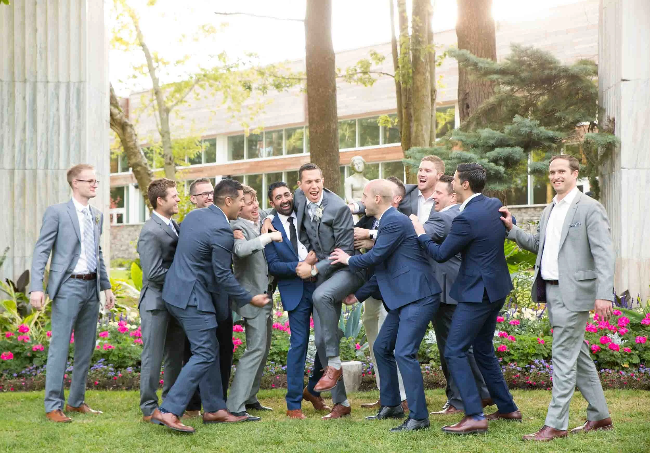 Candid groomsmen wrestling action moment in Guild Inn Estate gardens