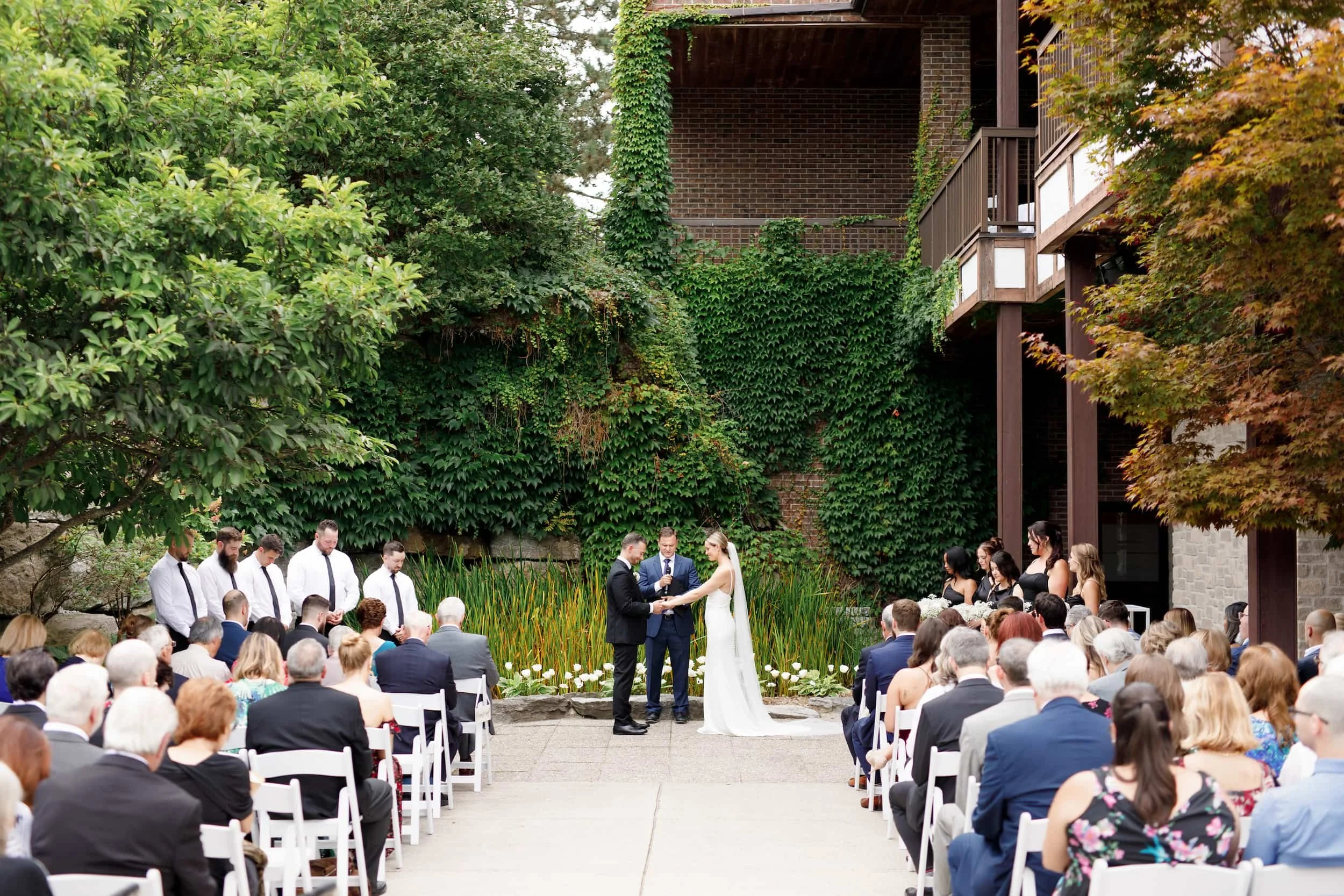 Outdoor wedding ceremony beneath ivy-covered facade at The Manor Event Venue in King, Ontario