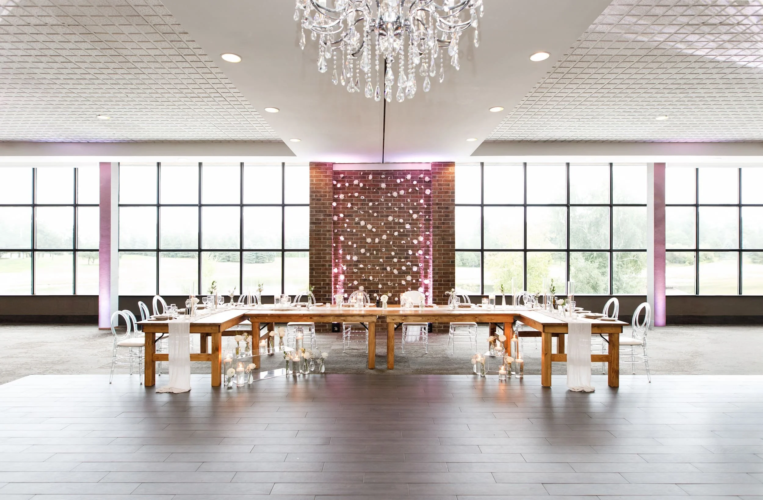 Reception space with chandelier and long harvest tables at The Manor Event Venue in King, Ontario