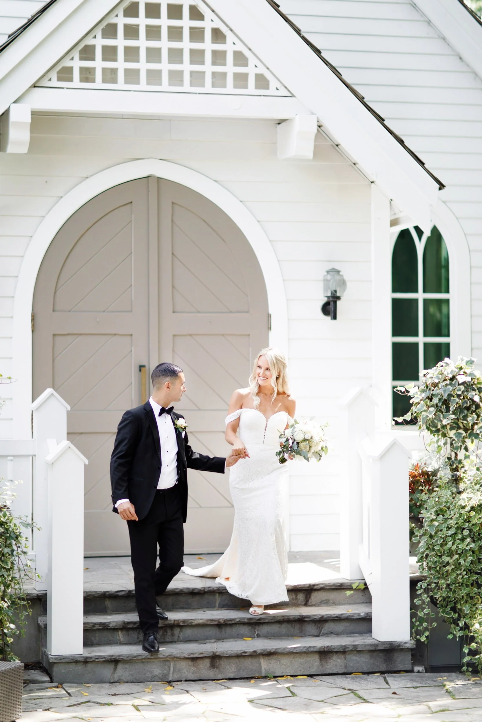 Couple walking outside white chapel at The Doctor’s House in Kleinburg, Ontario