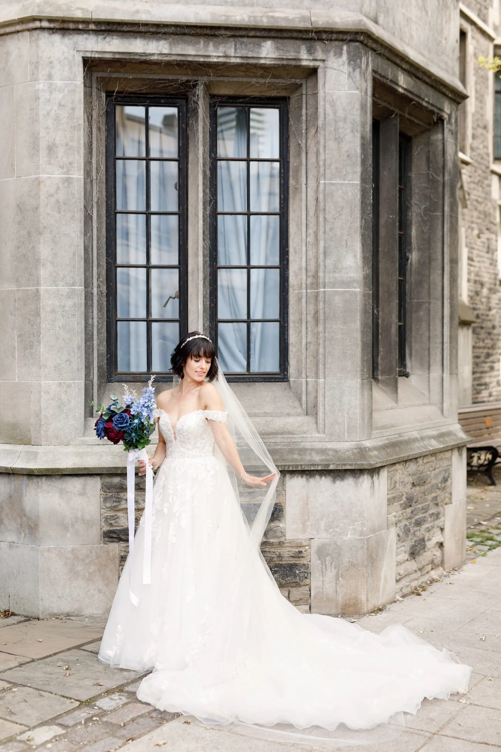 Bridal portrait beside Gothic stone facade at Victoria College, University of Toronto in Toronto, Ontario