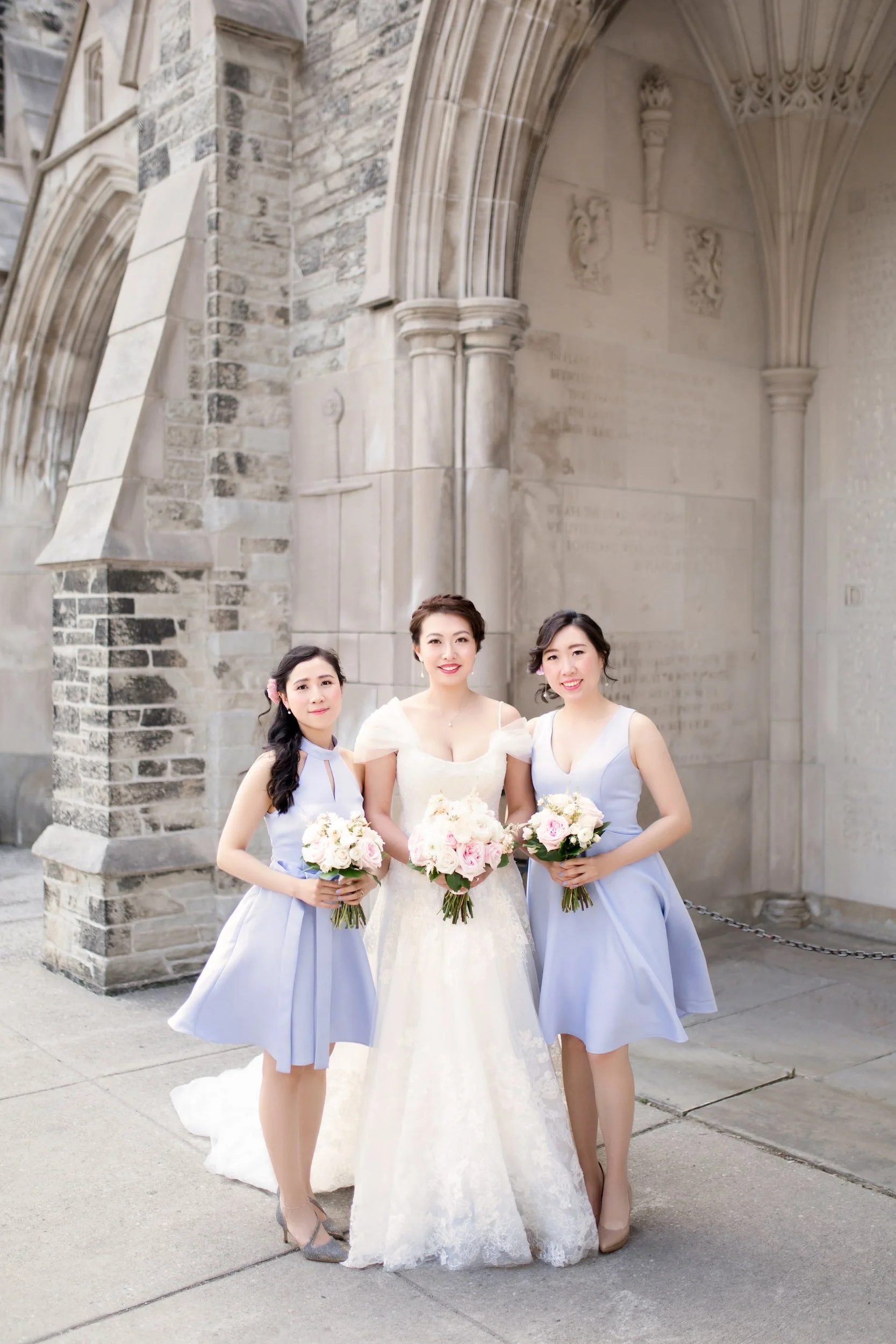 Bride and bridesmaids beneath stone arches at Knox College, University of Toronto in Toronto, Ontario