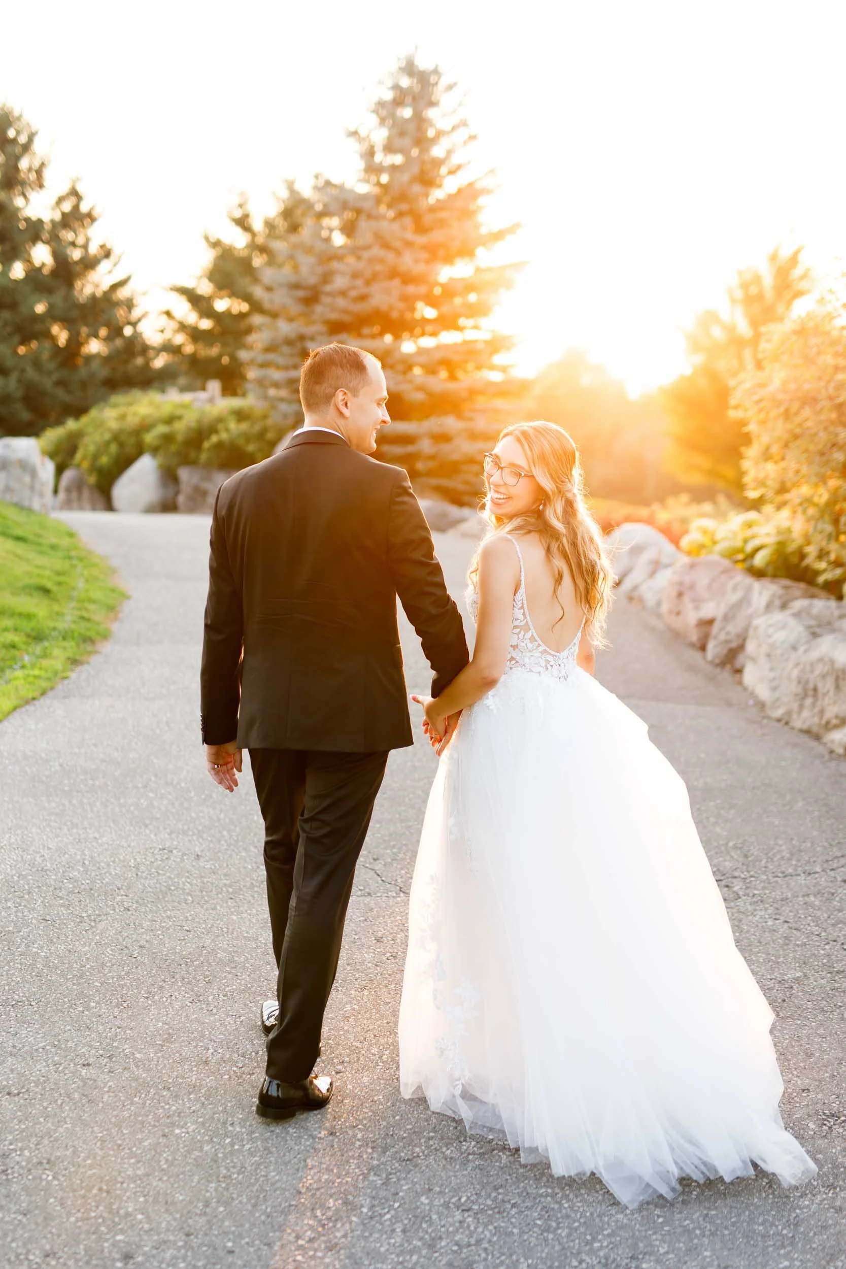 Bride and groom walking at sunset along garden path at Whistle Bear Golf Club in Cambridge, Ontario