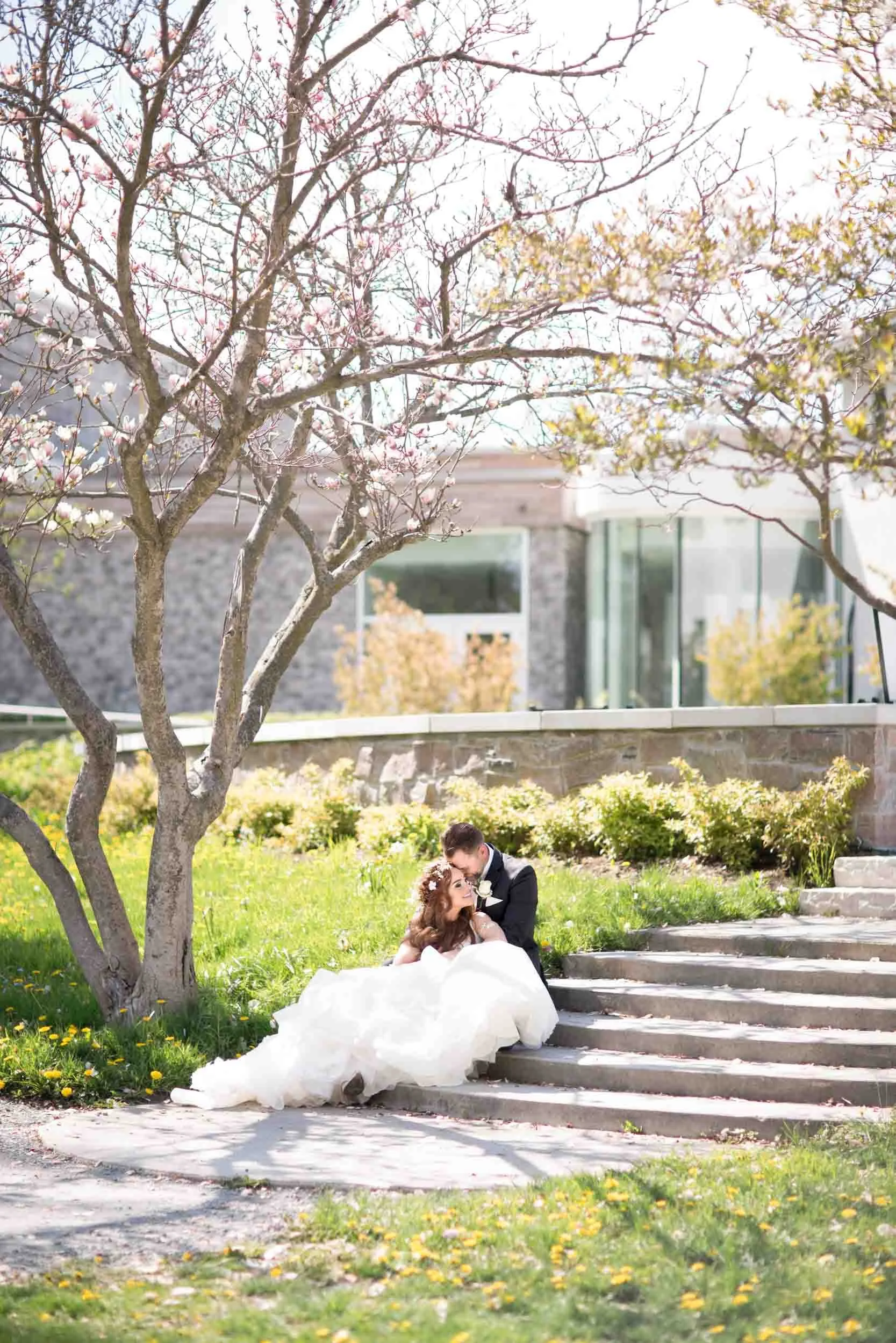 Bride and groom portrait sitting on sun-drenched step in Guild Inn Estate gardens in Scarborough