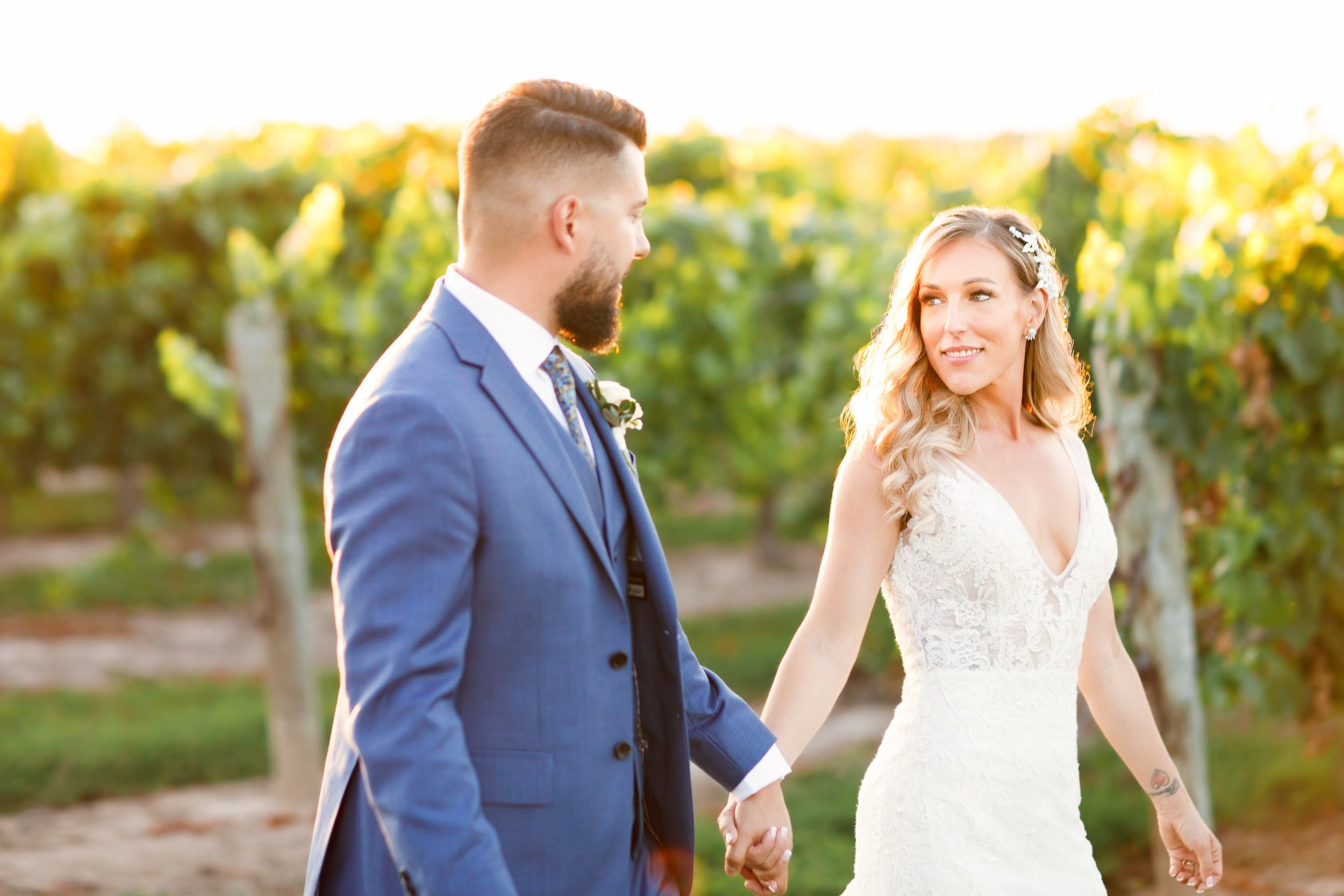 Bride and groom walking at golden hour through Niagara vineyard