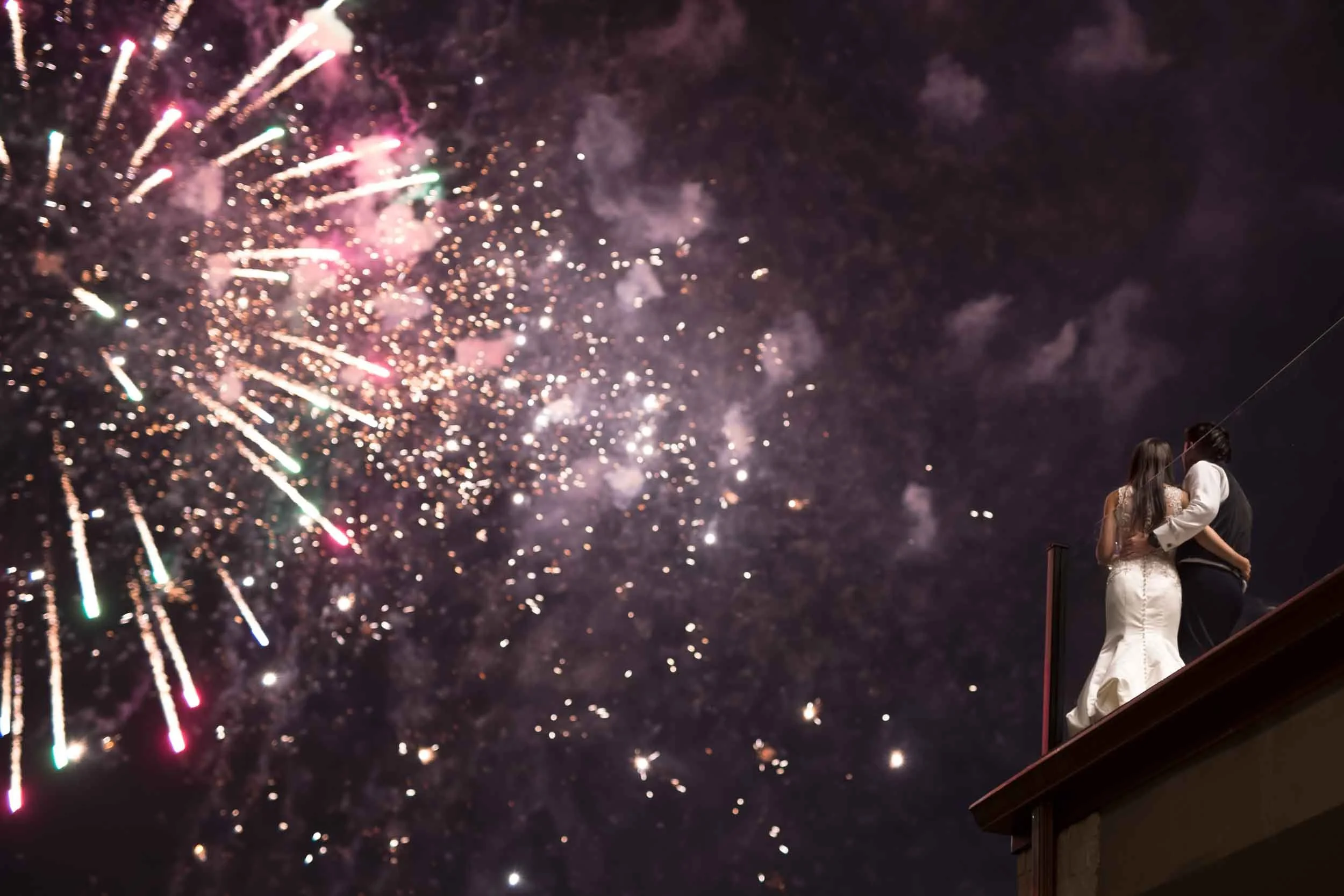 Bride and groom watching grand fireworks display over the Arlington Estate balcony at night in Vaughan