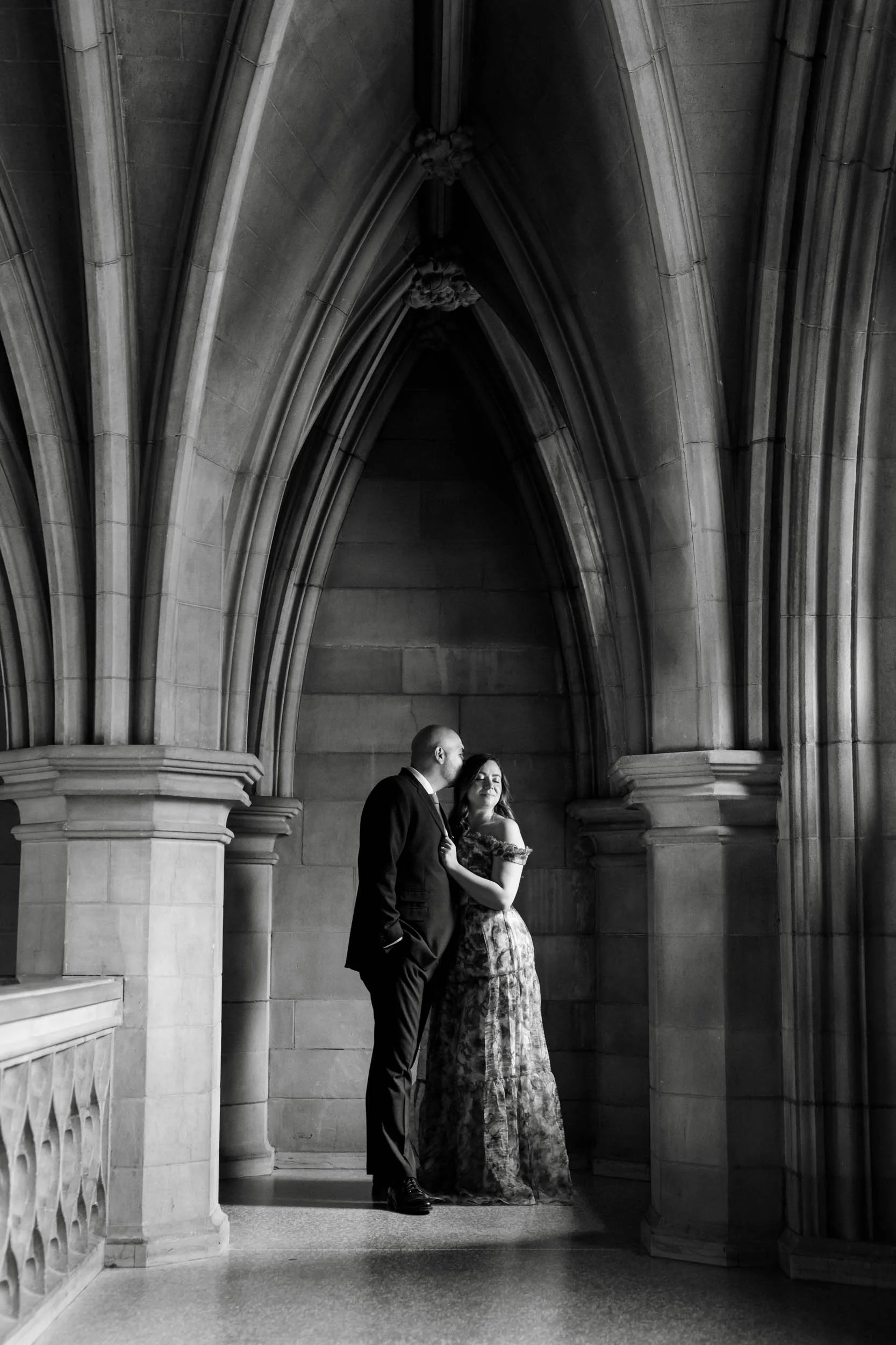 Romantic black and white engagement portrait in shadowed archway at Knox College, University of Toronto in Toronto, Ontario