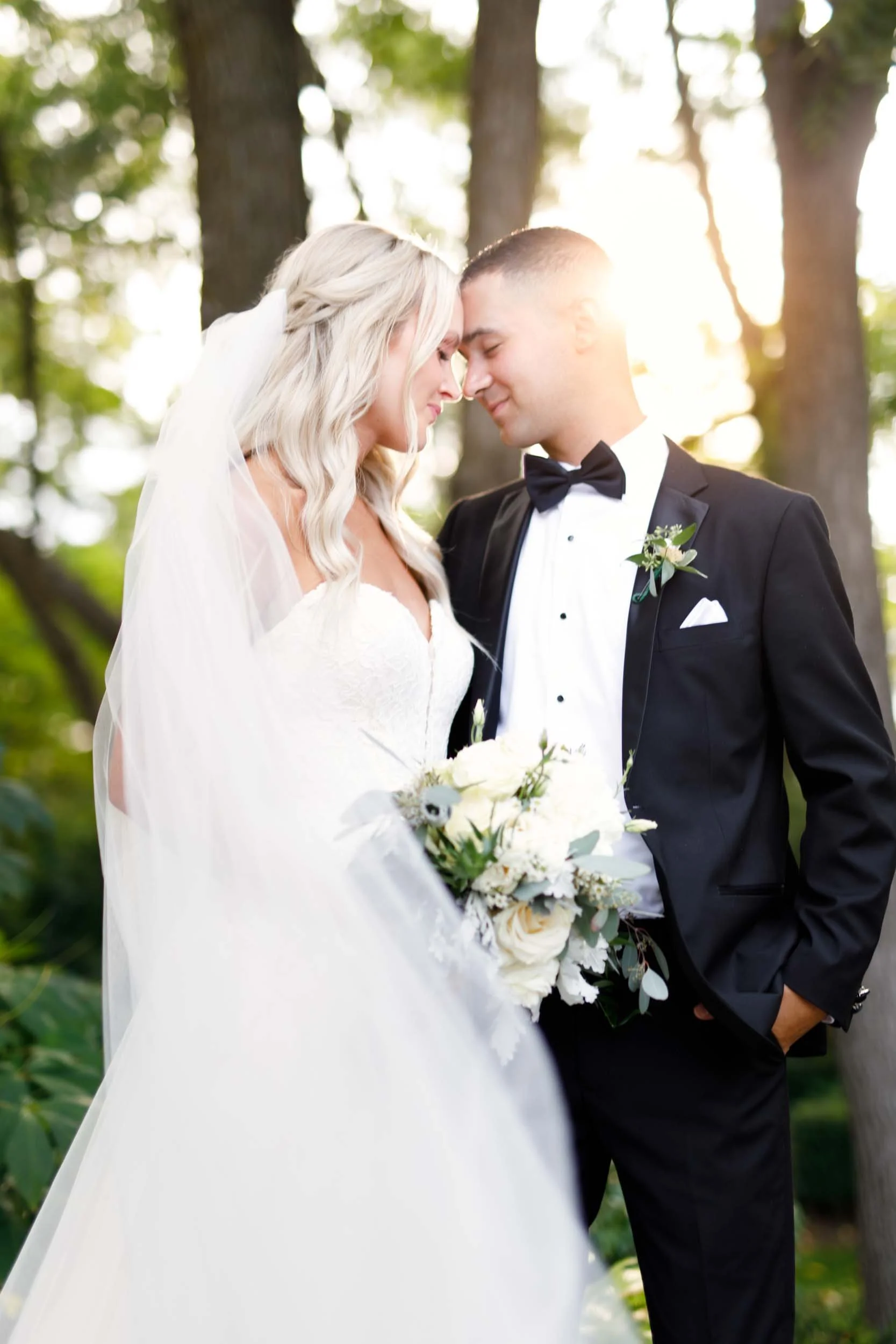 Intimate bridal portrait with sunflare over grooms shoulder beneath trees at The Doctor’s House in Kleinburg, Ontario
