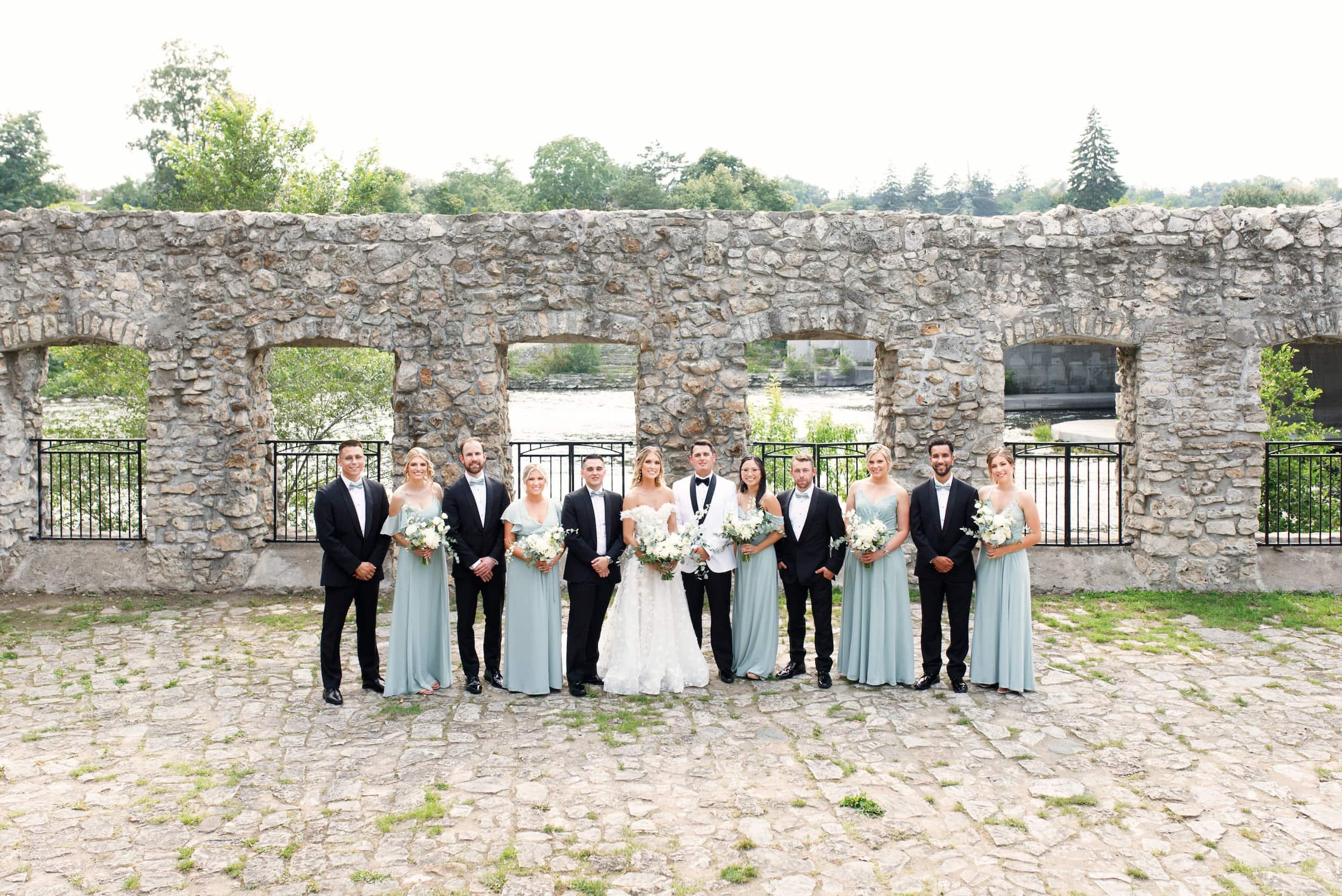 Wedding party standing together at the stone Mill Race Park in Cambridge, Ontario