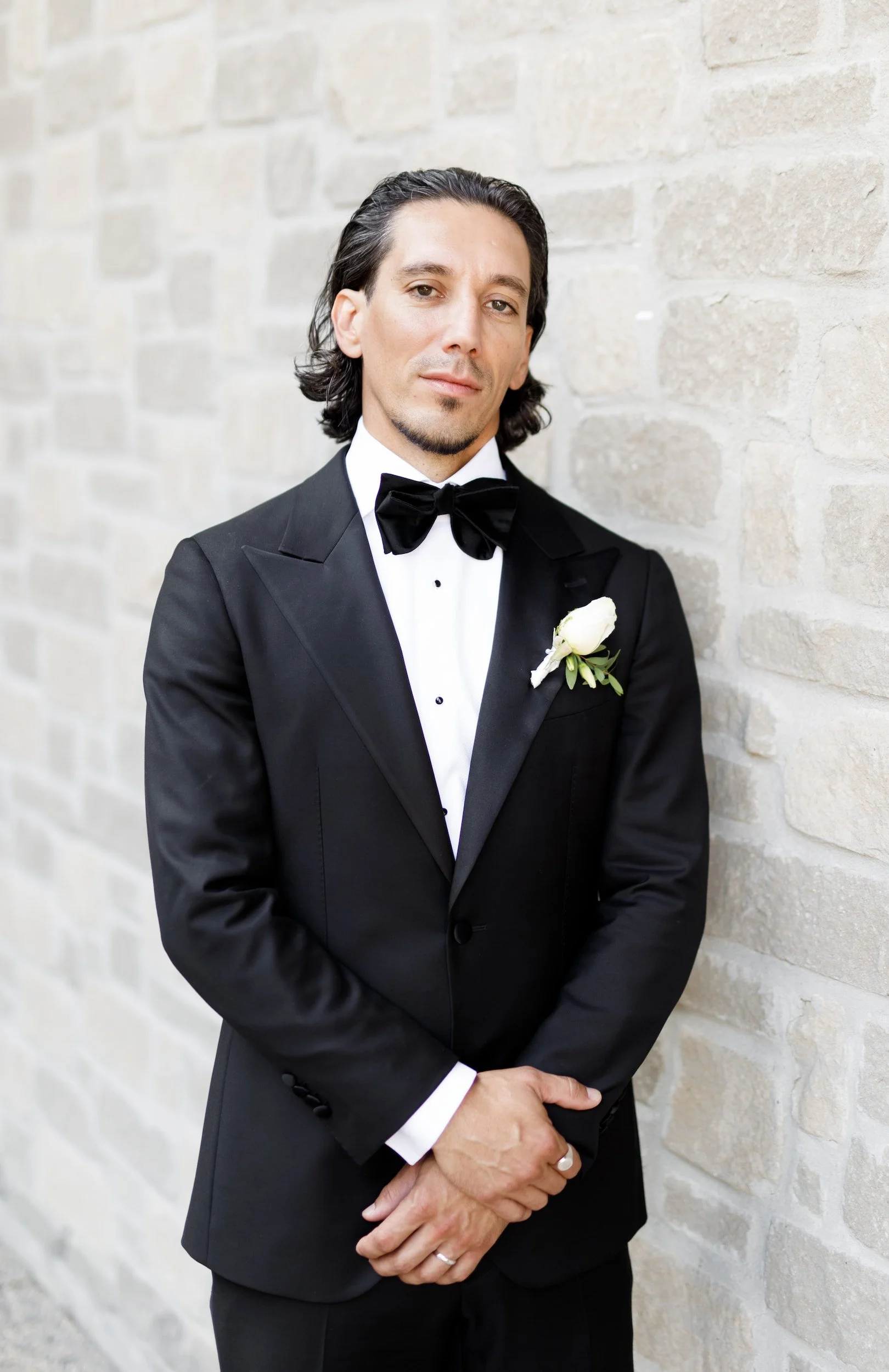 Groom portrait in black tuxedo against stone wall at The Manor Event Venue wedding in King, Ontario