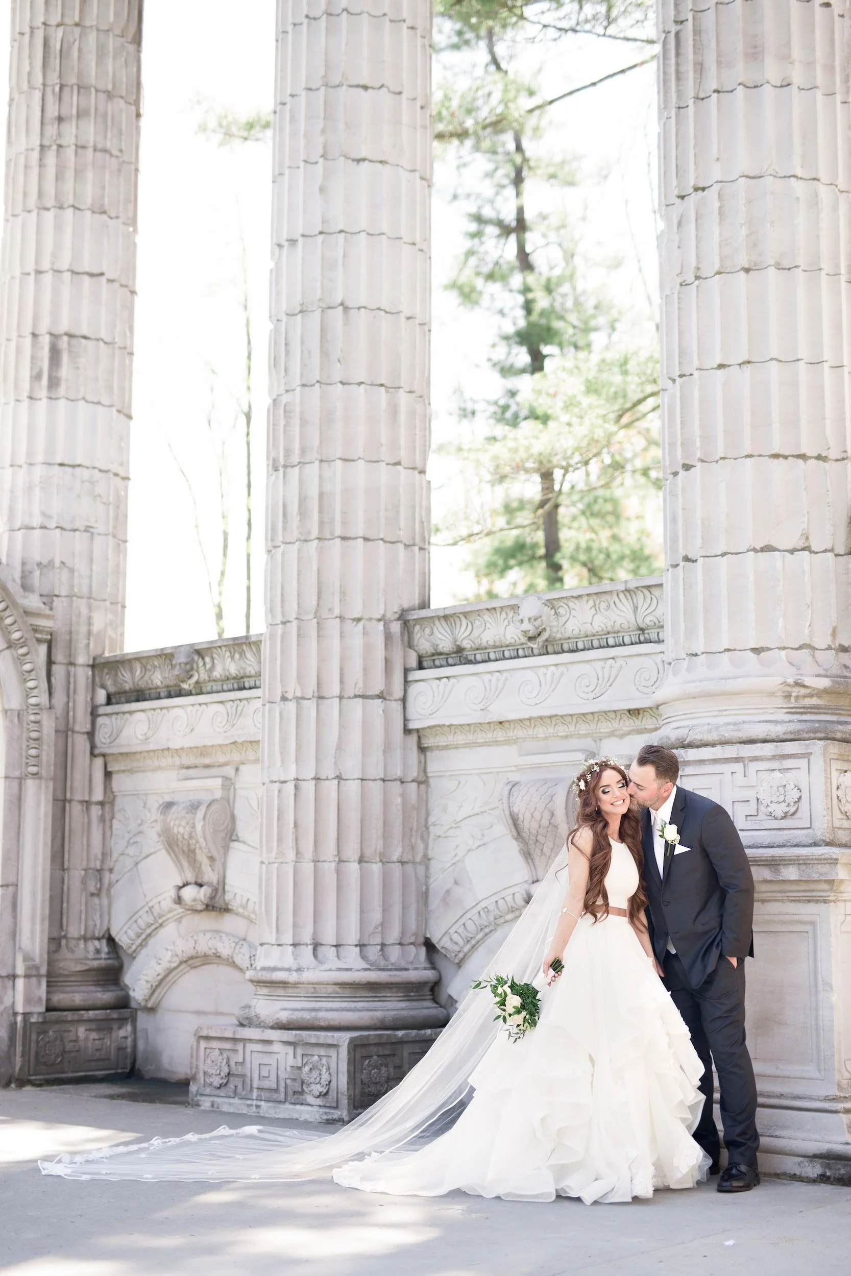Bride and groom portrait beneath classical columns at Guild Inn Estate