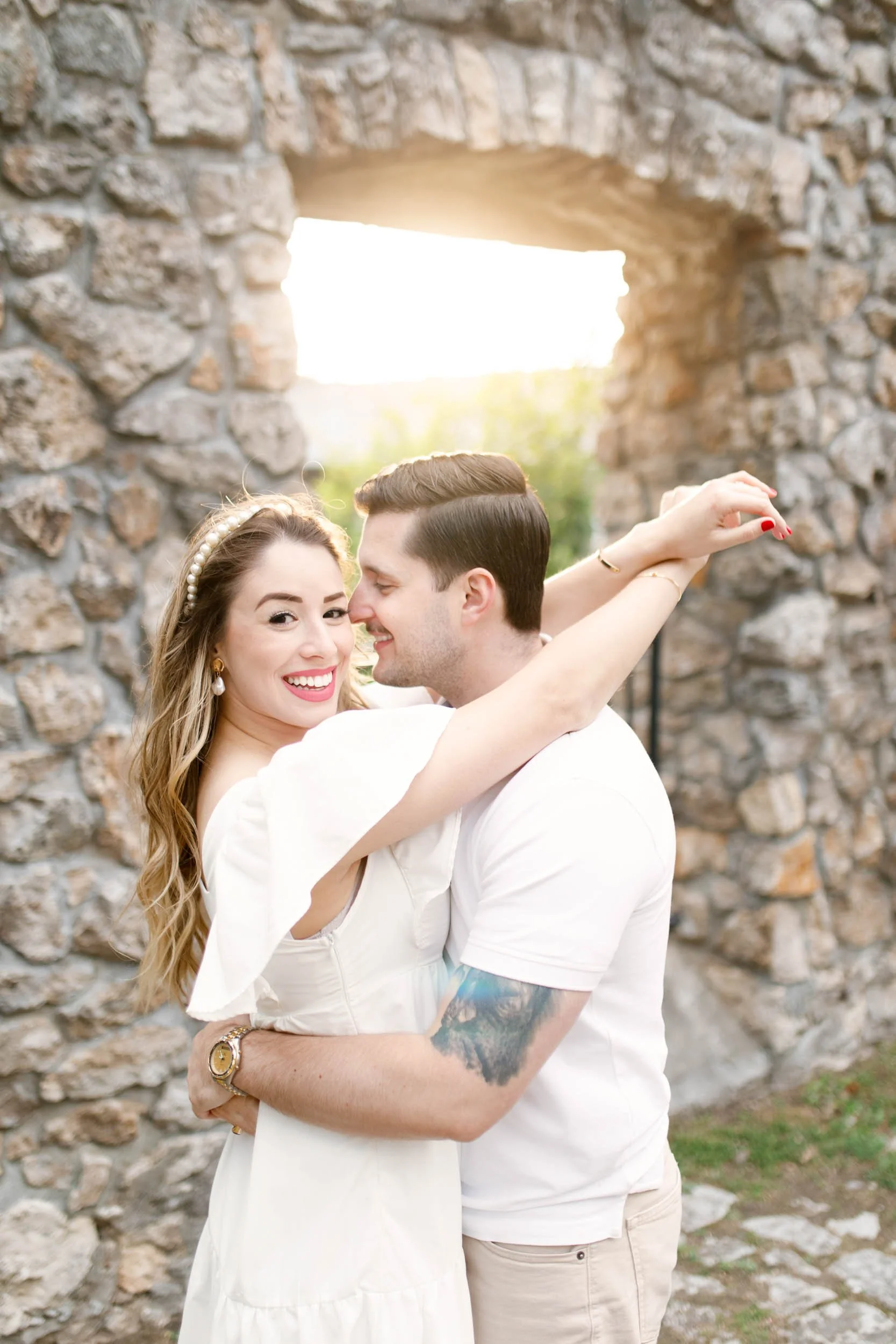 Engagement portrait framed by limestone archways at Mill Race Park in Cambridge