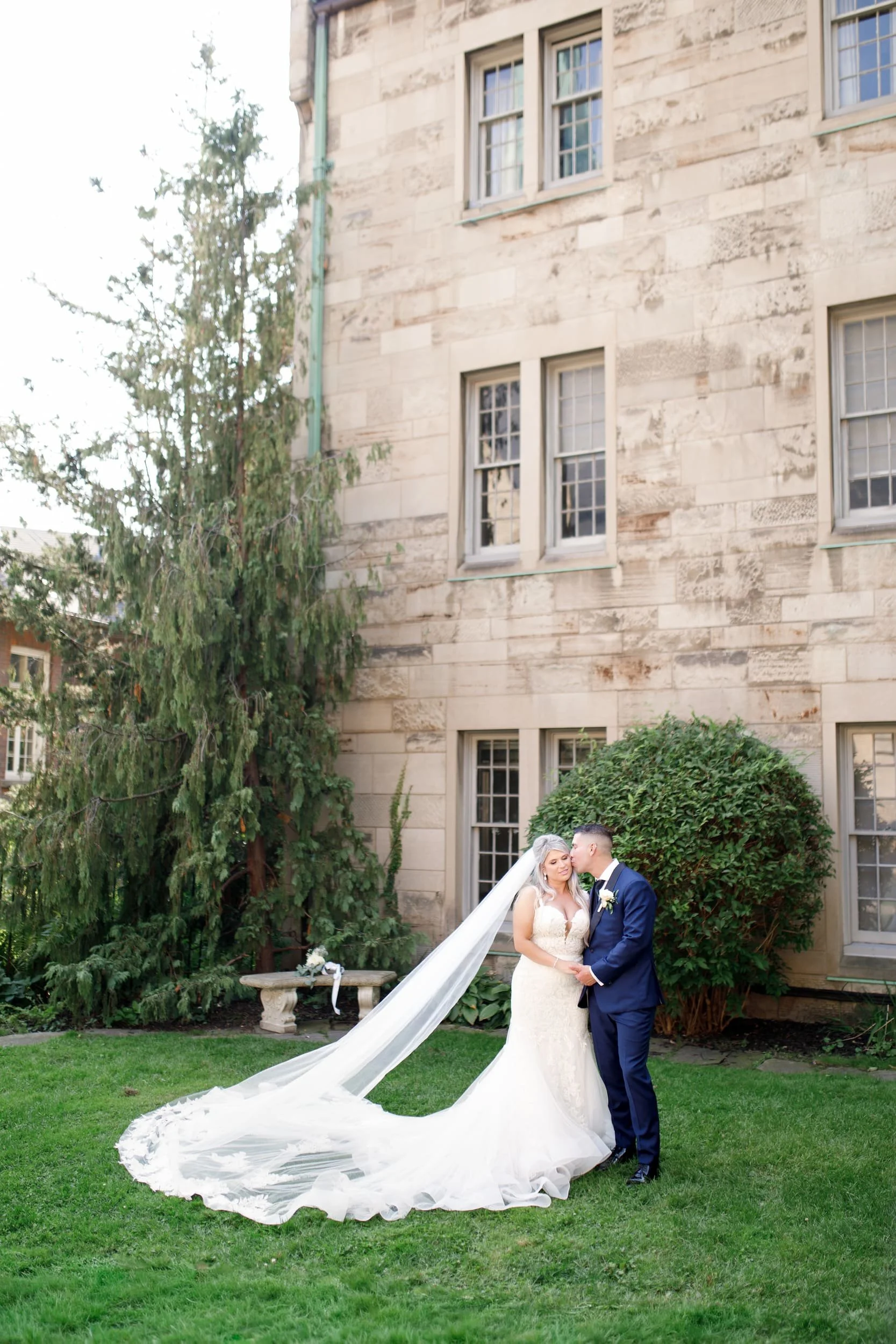 Bride and groom with flowing veil on the lawn at St. Michael’s College, University of Toronto in Toronto, Ontario