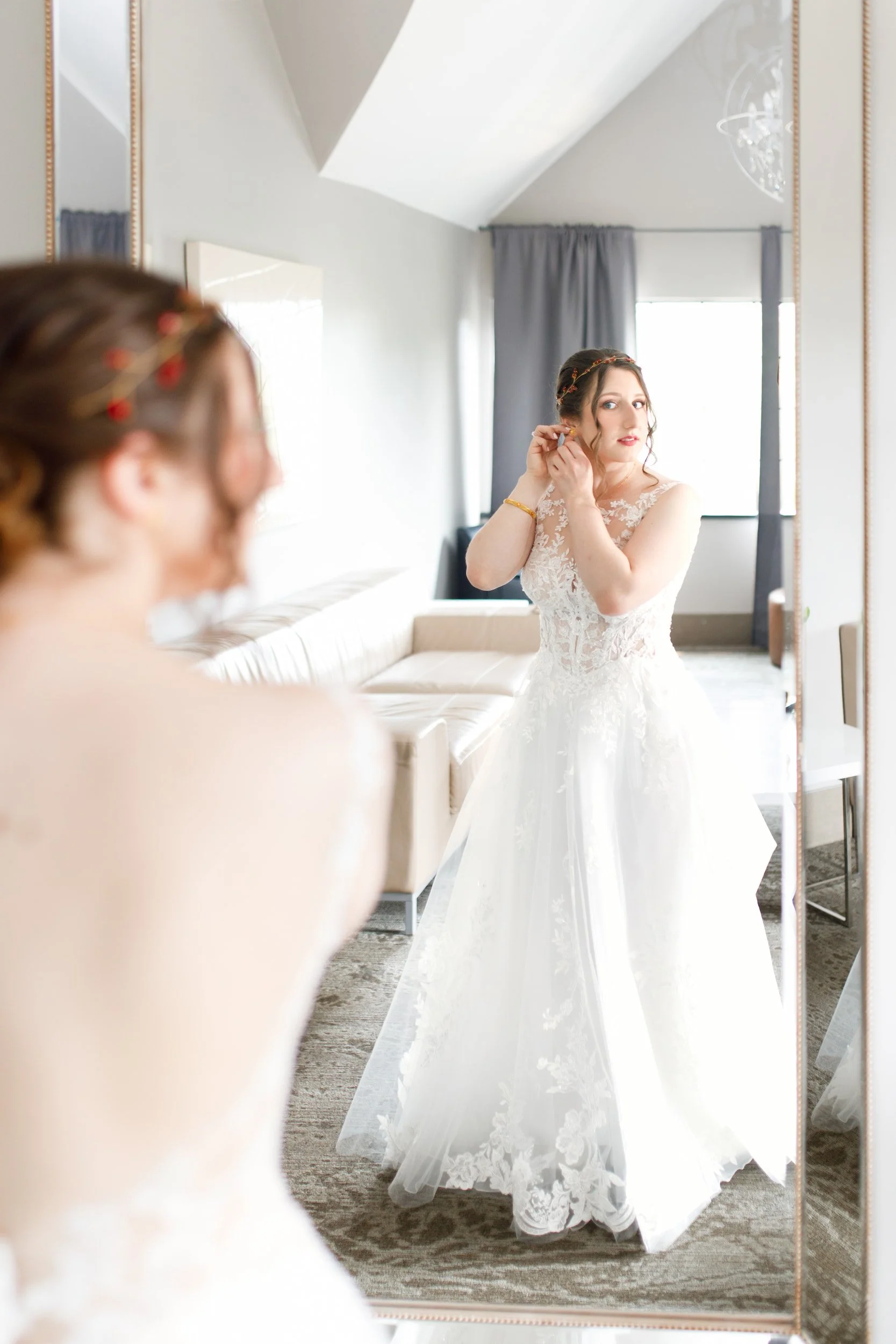 Bride adjusting earrings in natural light inside bridal suite at The Manor Event Venue in King, Ontario