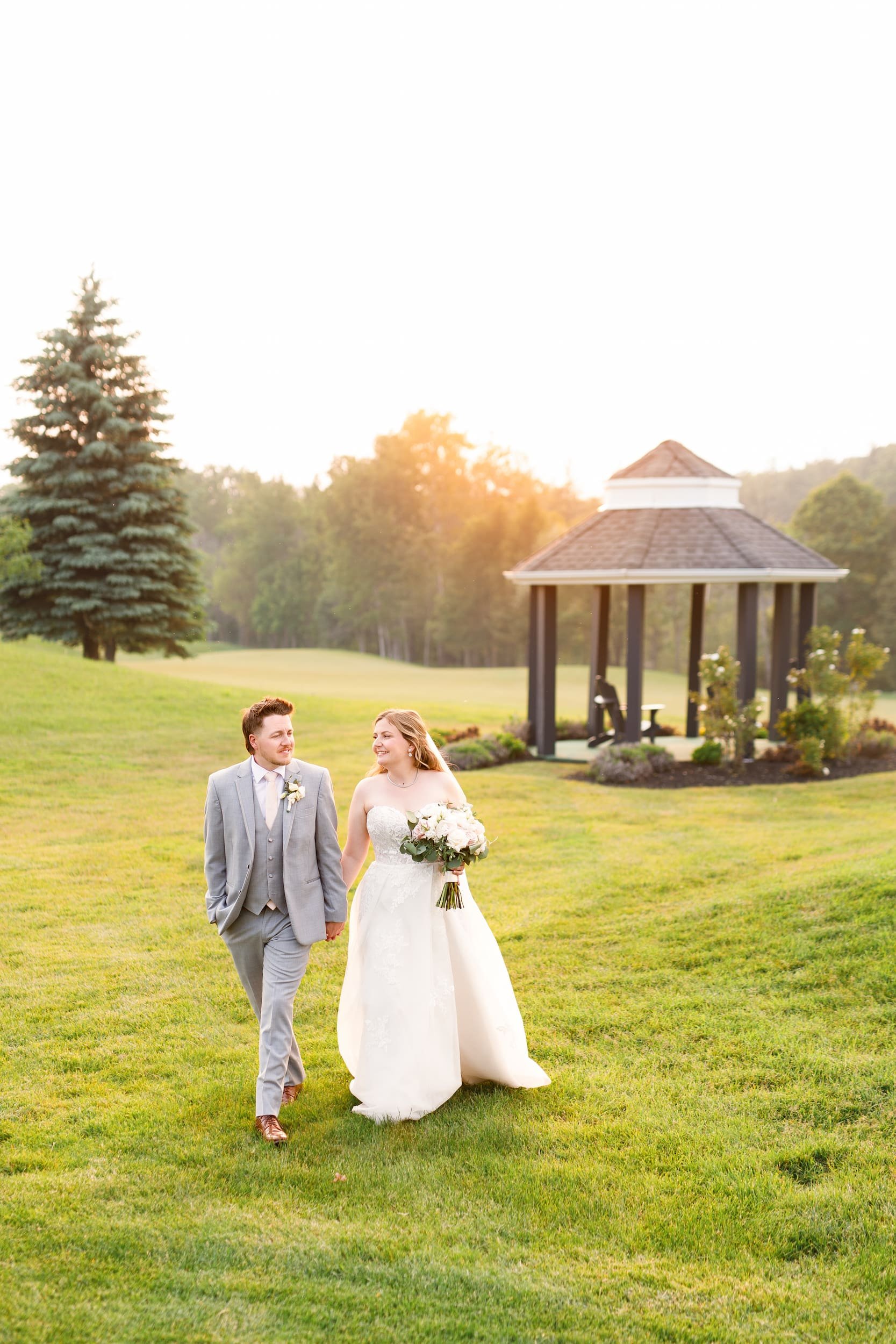Bride and groom walking across the golf course at sunset at Whistle Bear Golf Club in Cambridge, Ontario