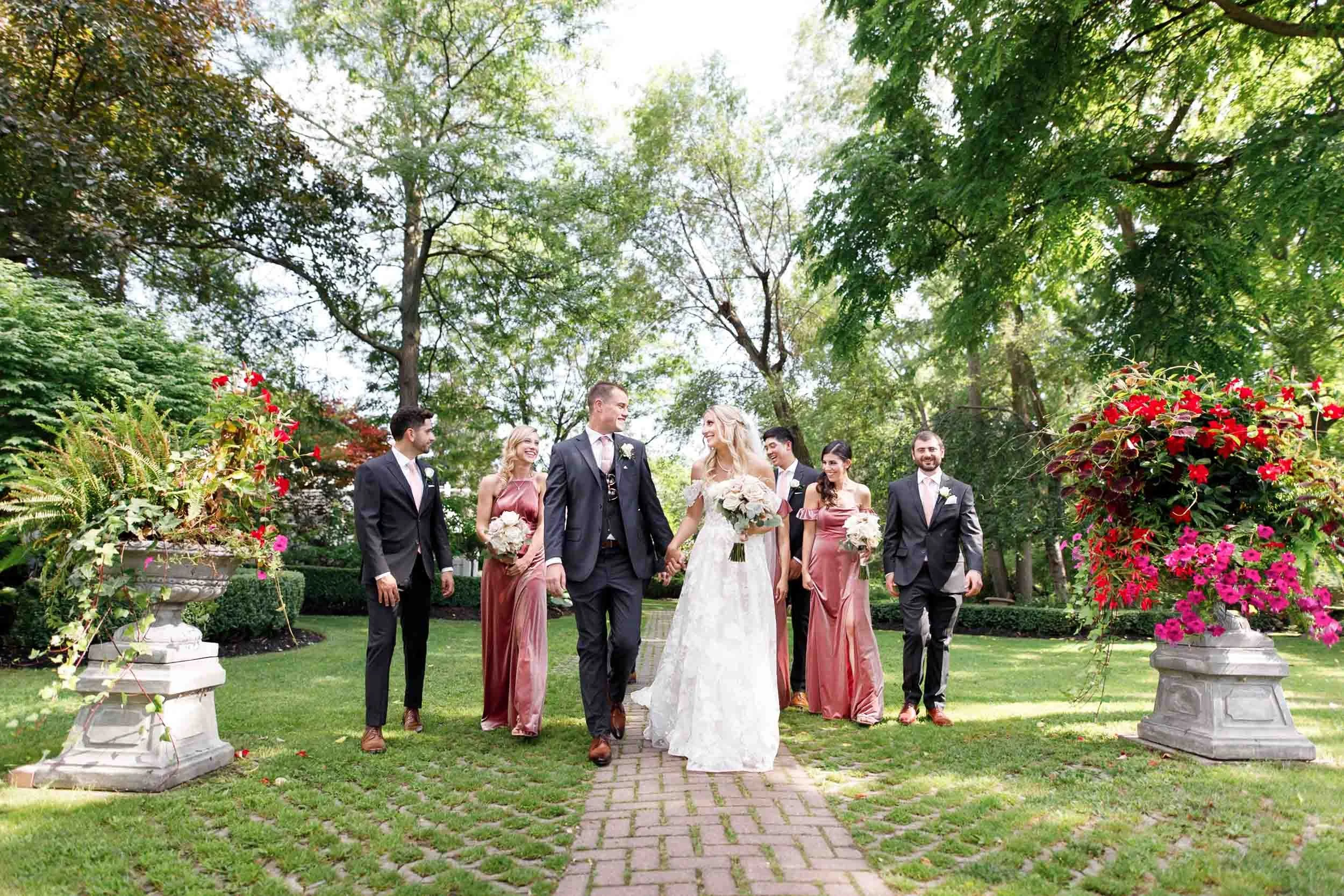 Wedding party walking through gardens at The Doctor’s House in Kleinburg, Ontario