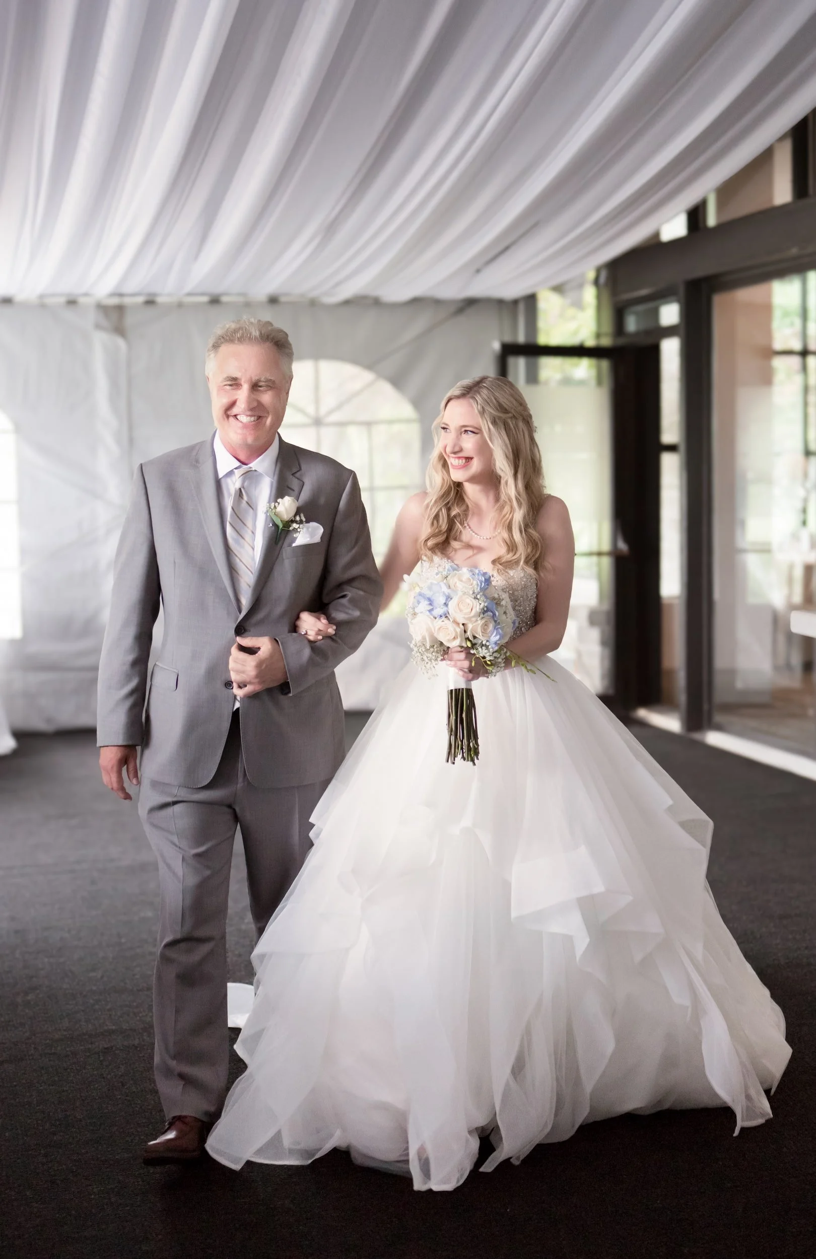 Bride walking down the aisle with her father beneath reception tent at The Manor Event Venue in King, Ontario