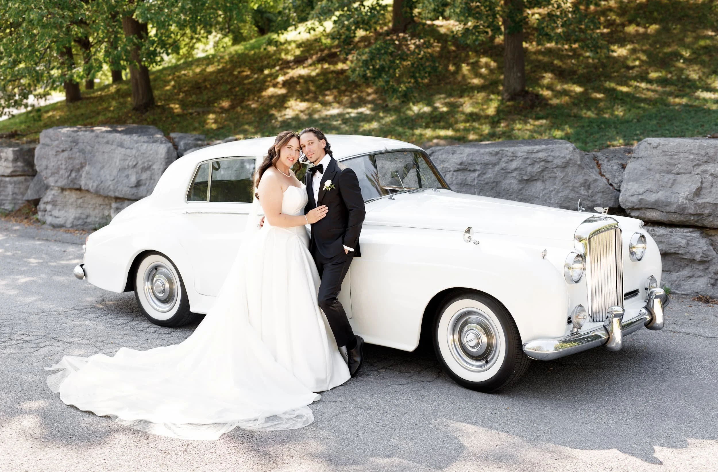 Bride and groom posing with vintage white Rolls Royce at The Manor Event Venue in King, Ontario