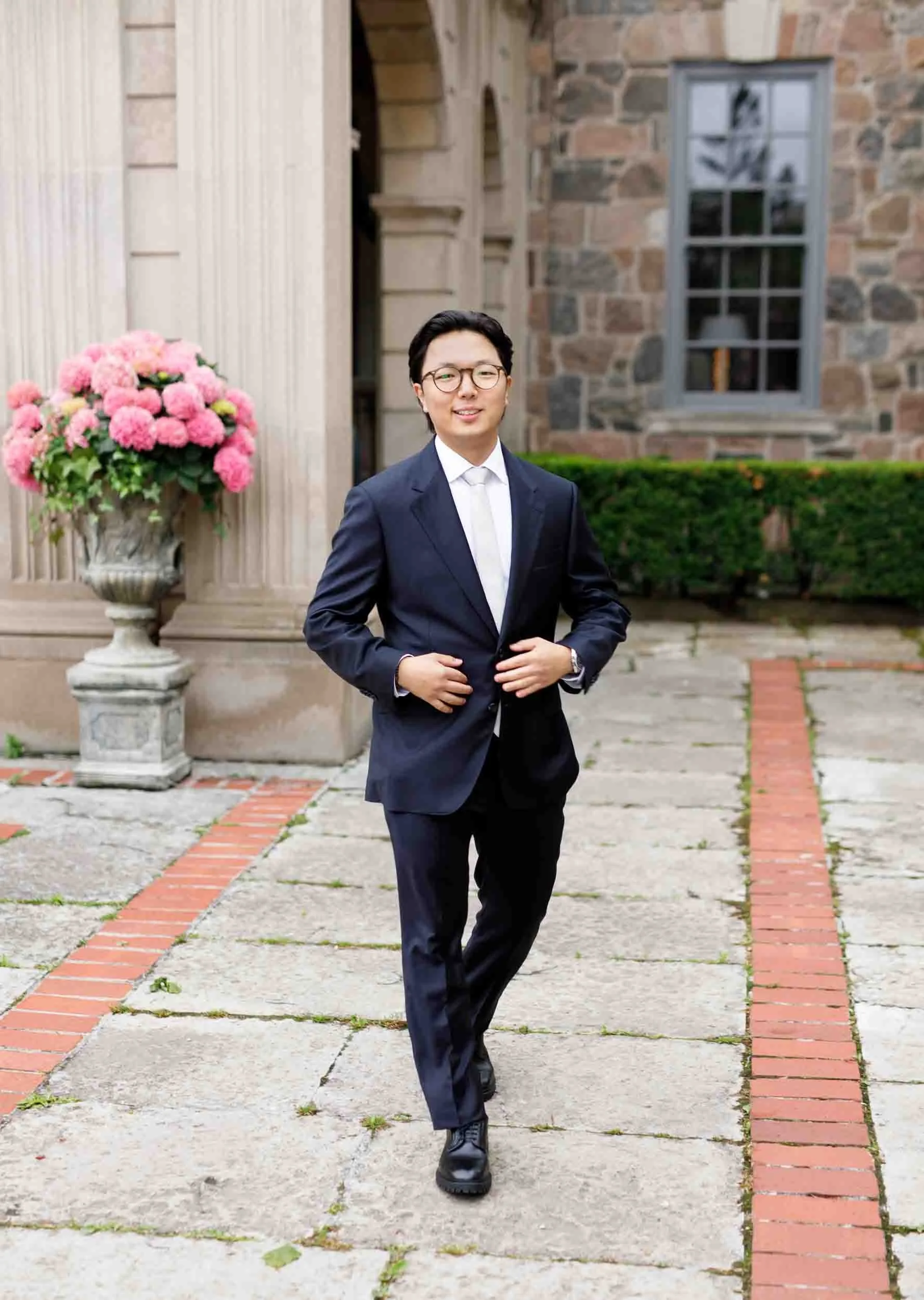Groom portrait walking through courtyard at Graydon Hall Manor