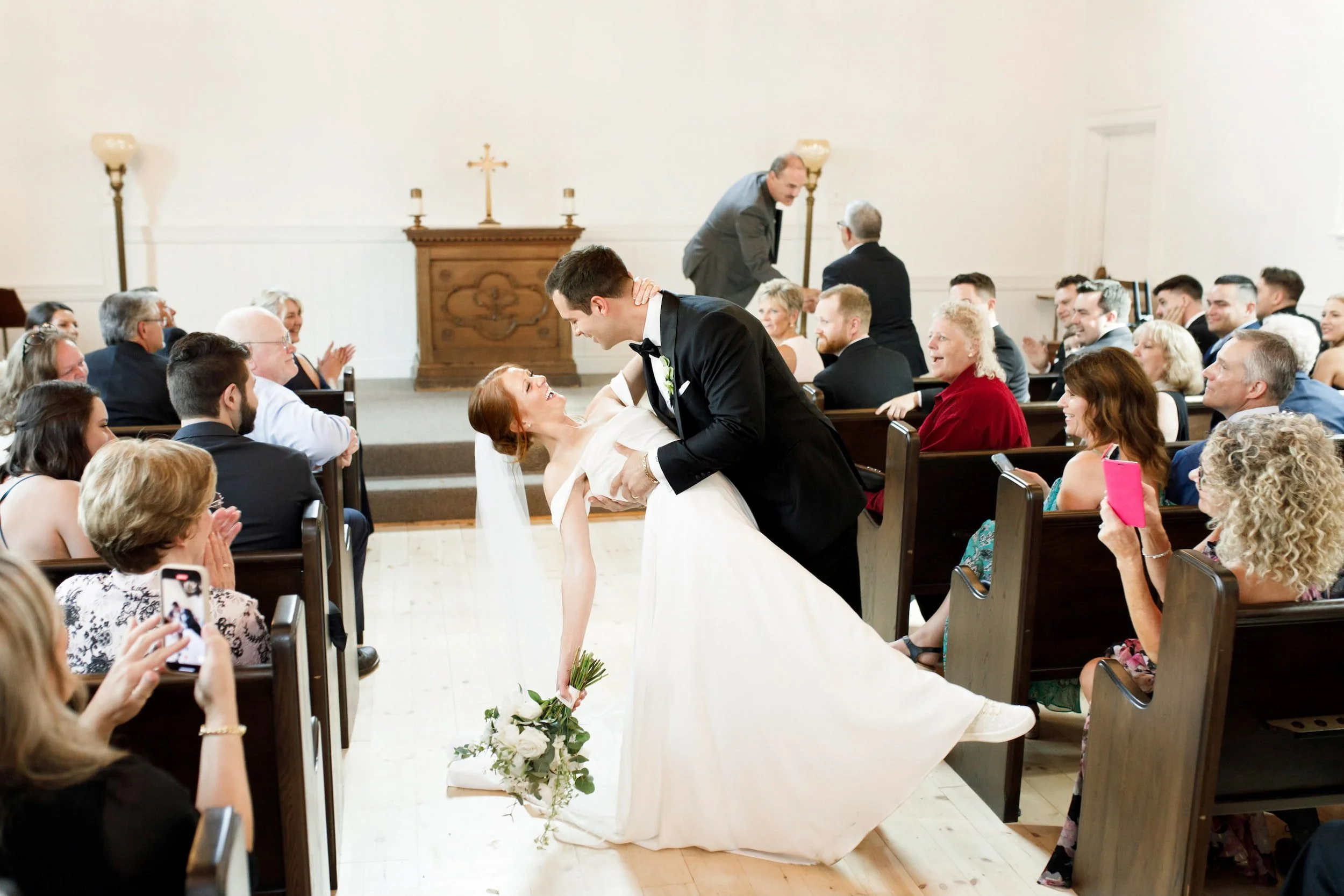 Joyful first kiss inside white chapel at The Doctor’s House in Kleinburg, Ontario