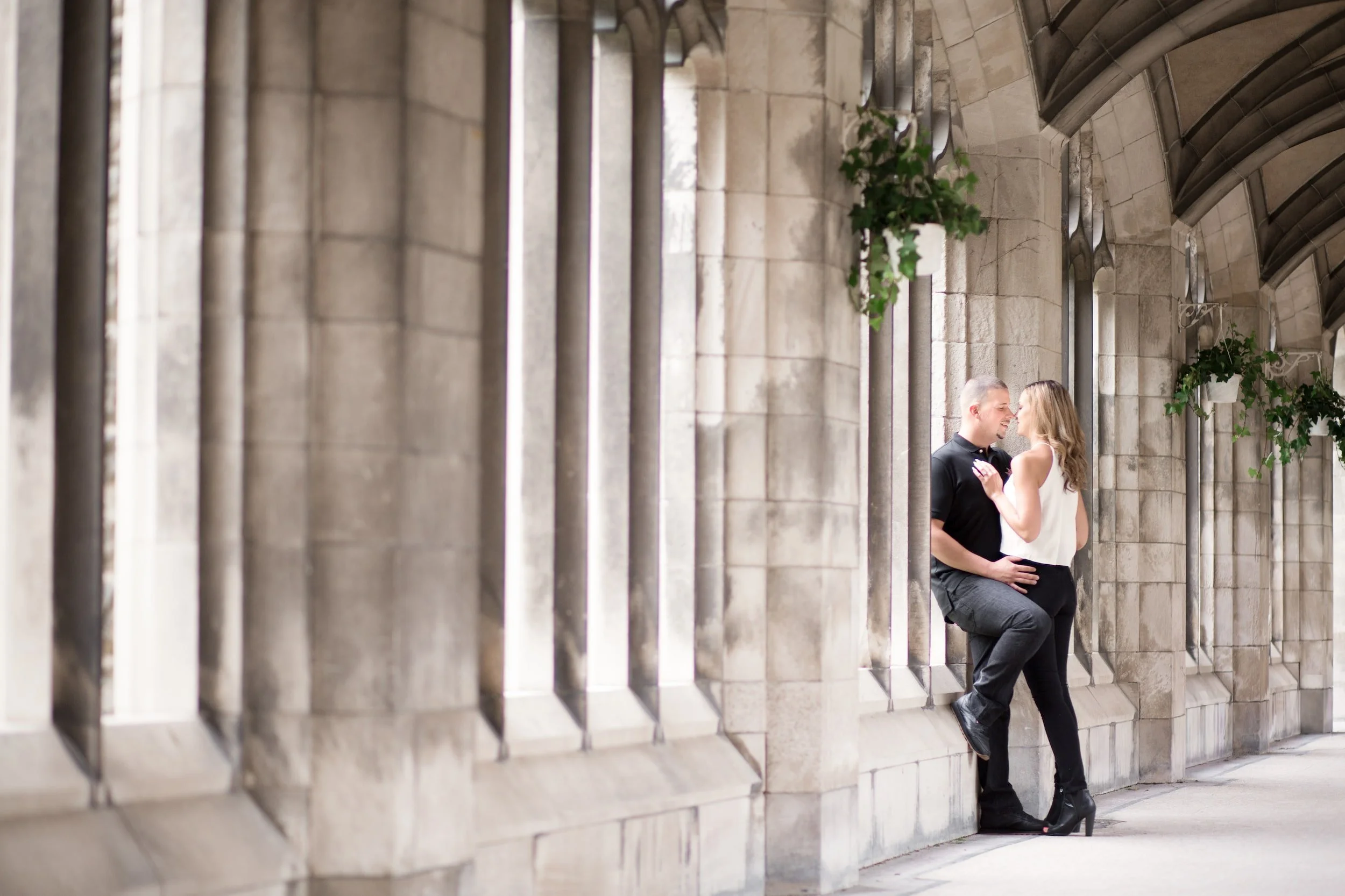 Engagement portrait beneath cloister columns at Knox College, University of Toronto in Toronto, Ontario
