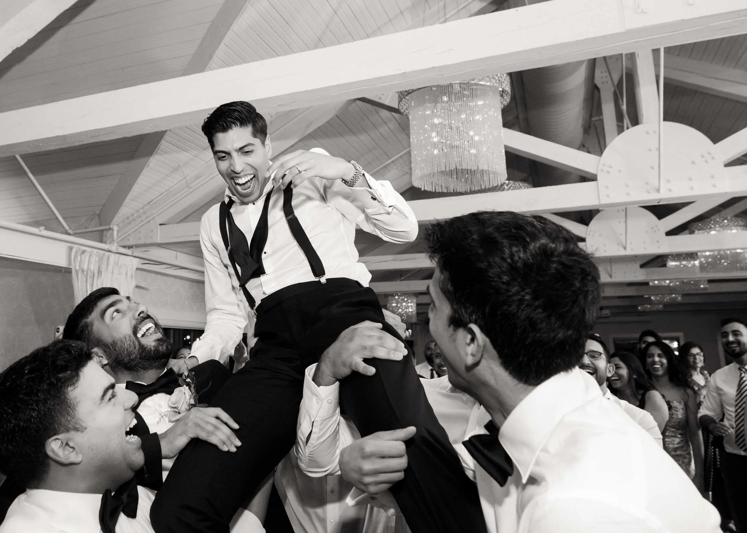 Black and white party shot with groom lifted by friends during reception celebration at Whistle Bear Golf Club in Cambridge, Ontario