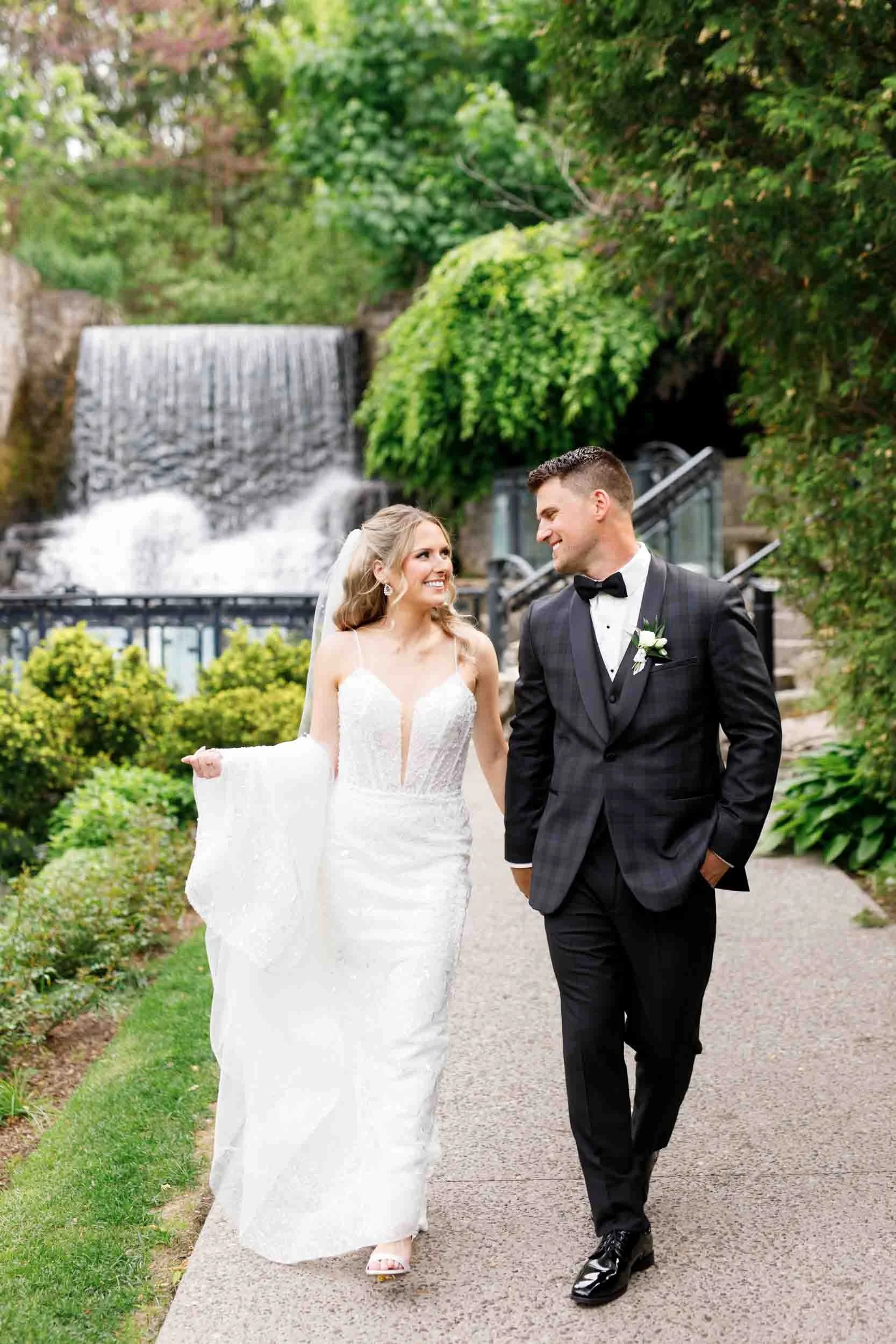 Bride and groom walking near the waterfall at the Ancaster Mill