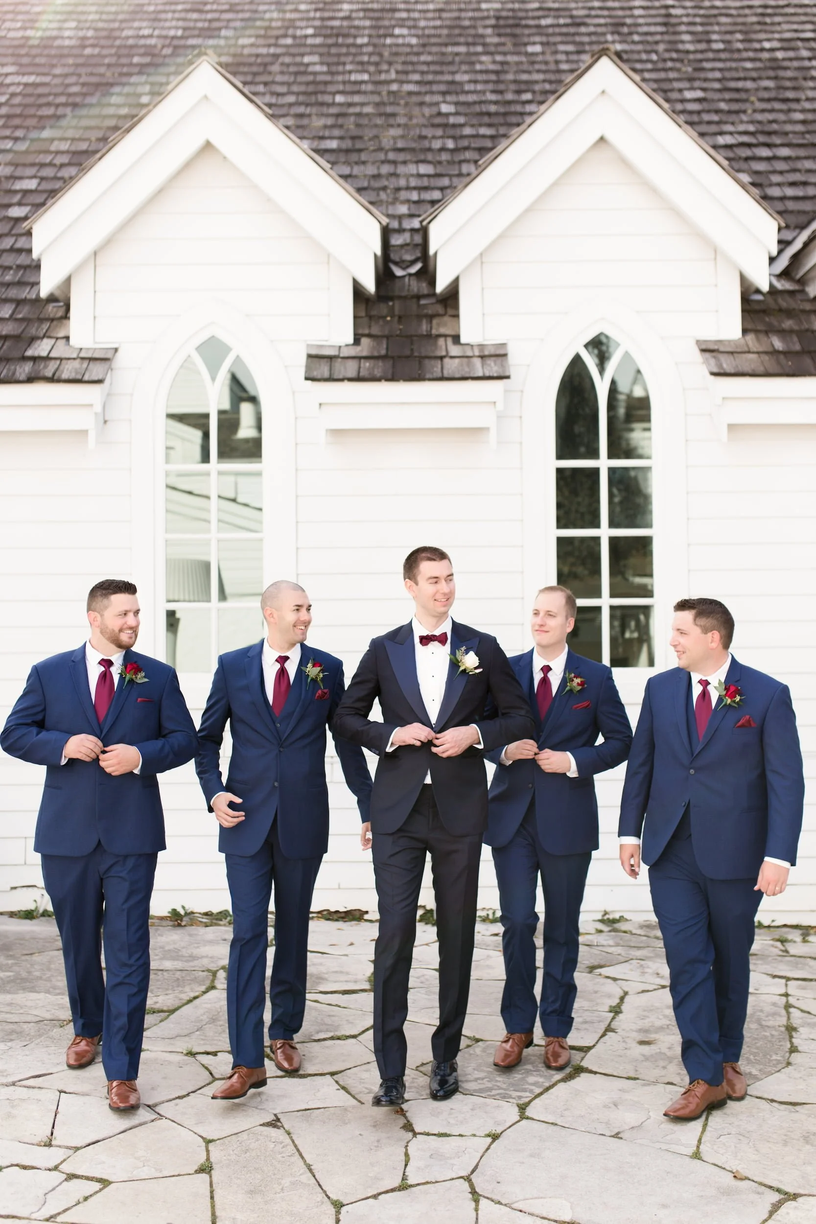 Groom and groomsmen outside white chapel at The Doctor’s House in Kleinburg, Ontario