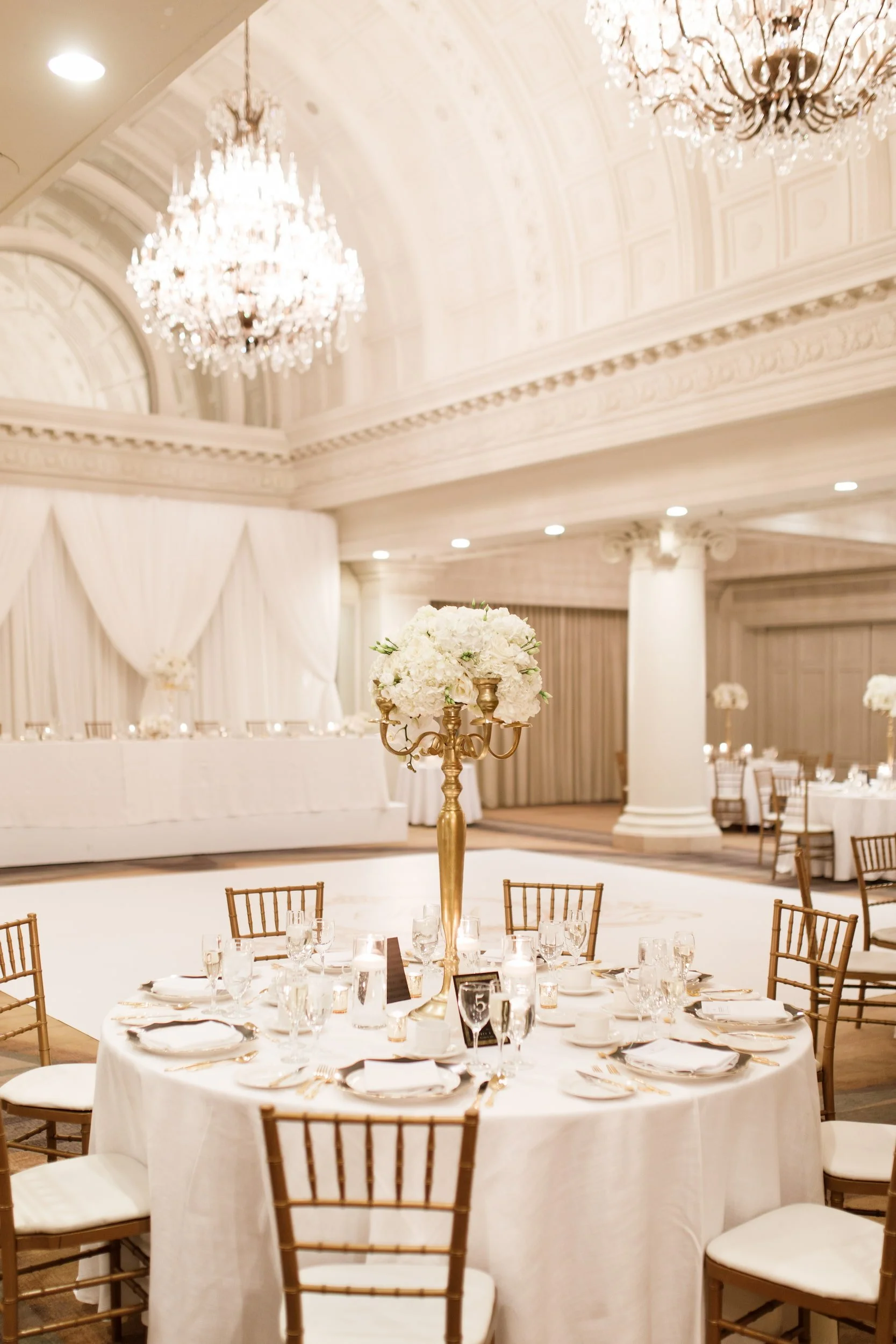 Reception tablescape beneath Vanity Fair Ballroom chandeliers at Omni King Edward Hotel