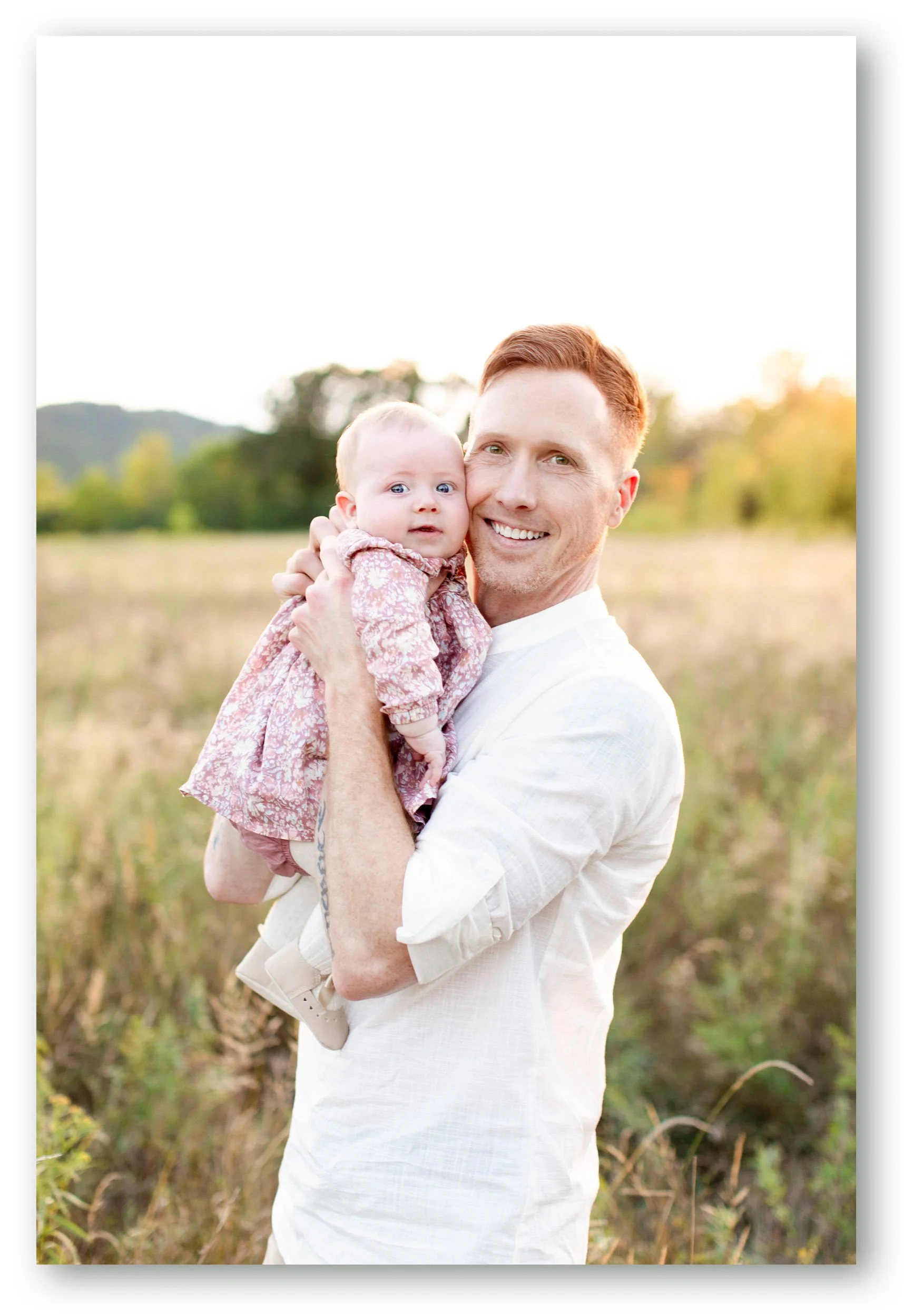 Portrait of wedding photographer Daniel Clements holding his daughter outdoors