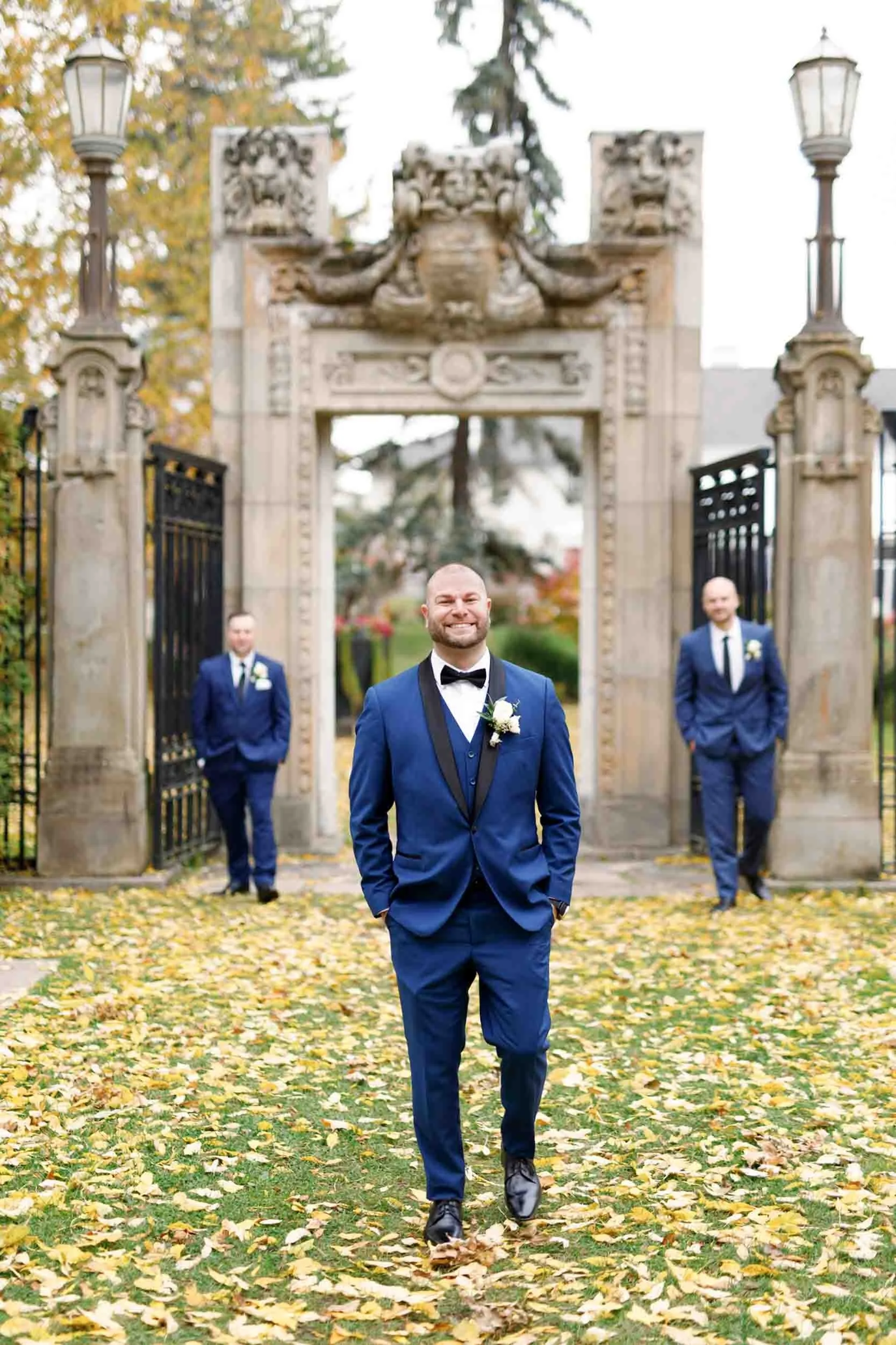 Groom portrait framed by Guild Inn Estate historic gate in autumn