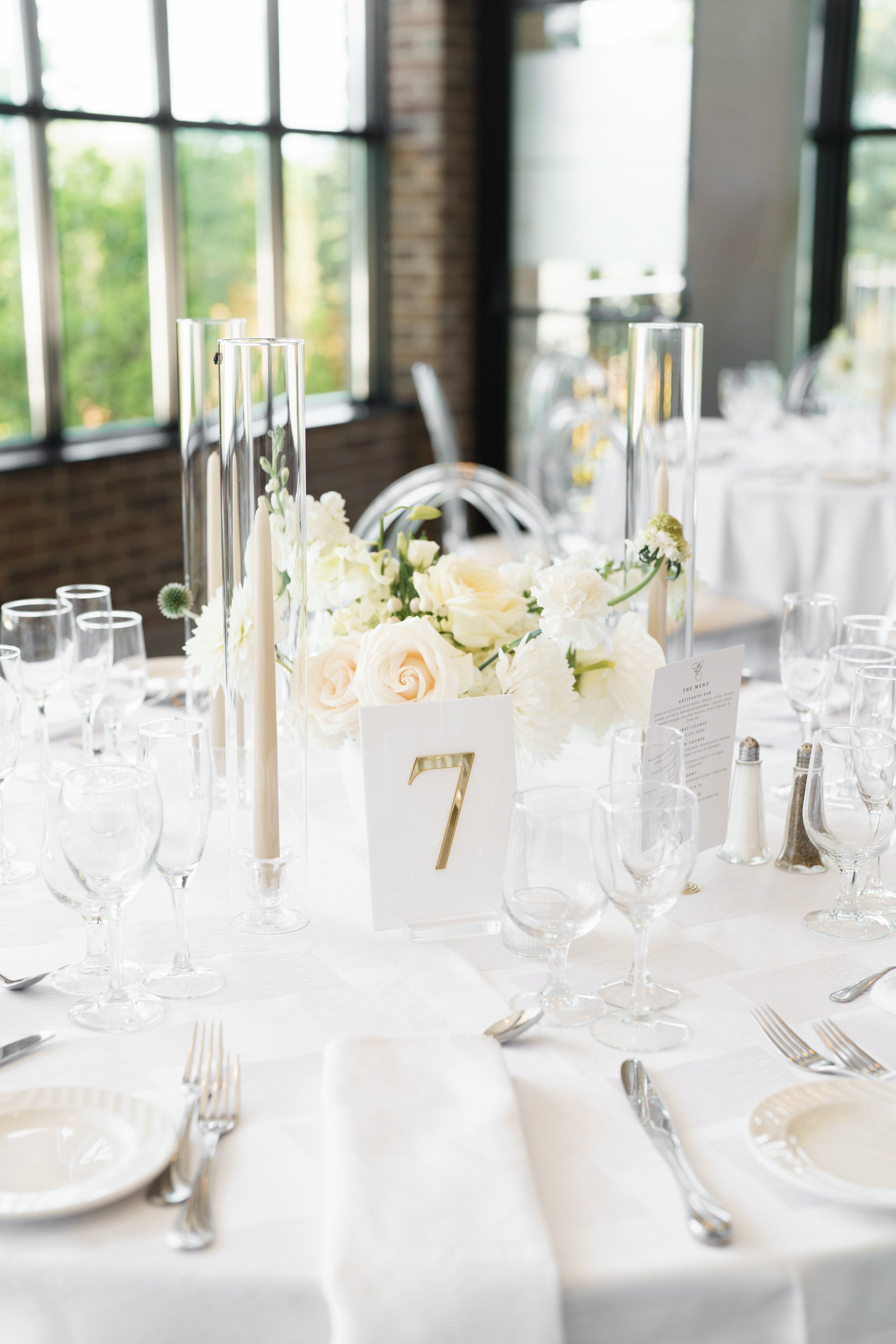 Wedding centrepiece with white florals and table number at The Manor Event Venue in King, Ontario